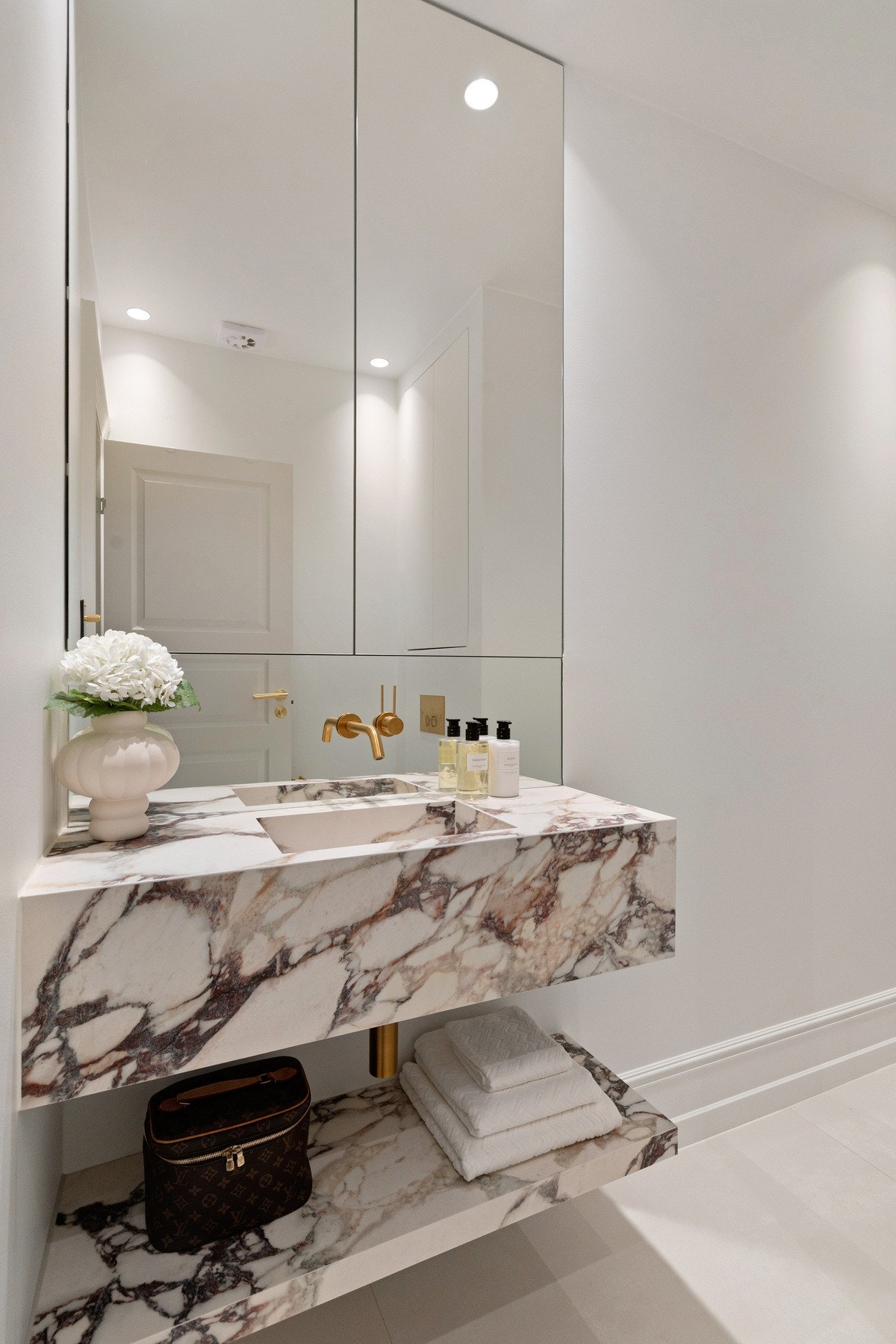 Badet er innredet med spesiallaget servant, veggskap med speildører, vegghengt WC, åpen dusjsone og frittstående badekar. Galleribilde