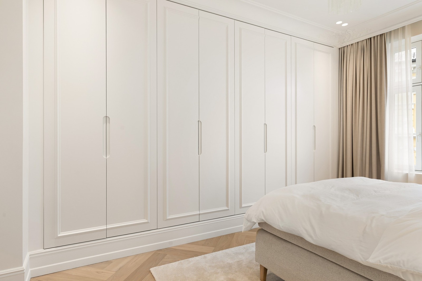 Romslig garderobeløsning med plassbygde skap langs hele veggen. Galleribilde