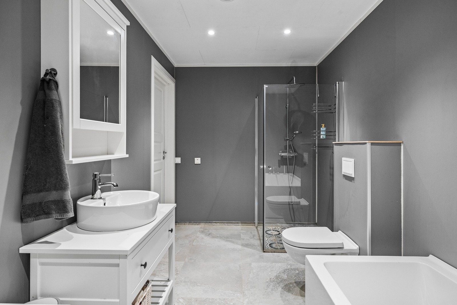 Badet har flislagt gulv med varme og downlightsbelysning. Galleribilde