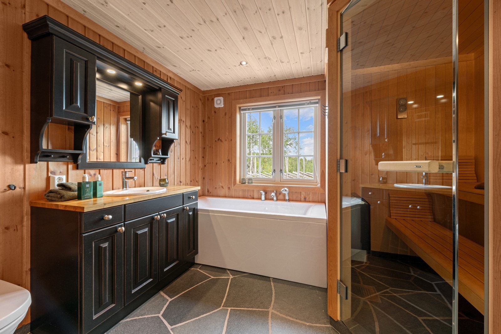 Hovedbaderom med plassbygget innredning, badekar, dusj, wc og badstue. Galleribilde