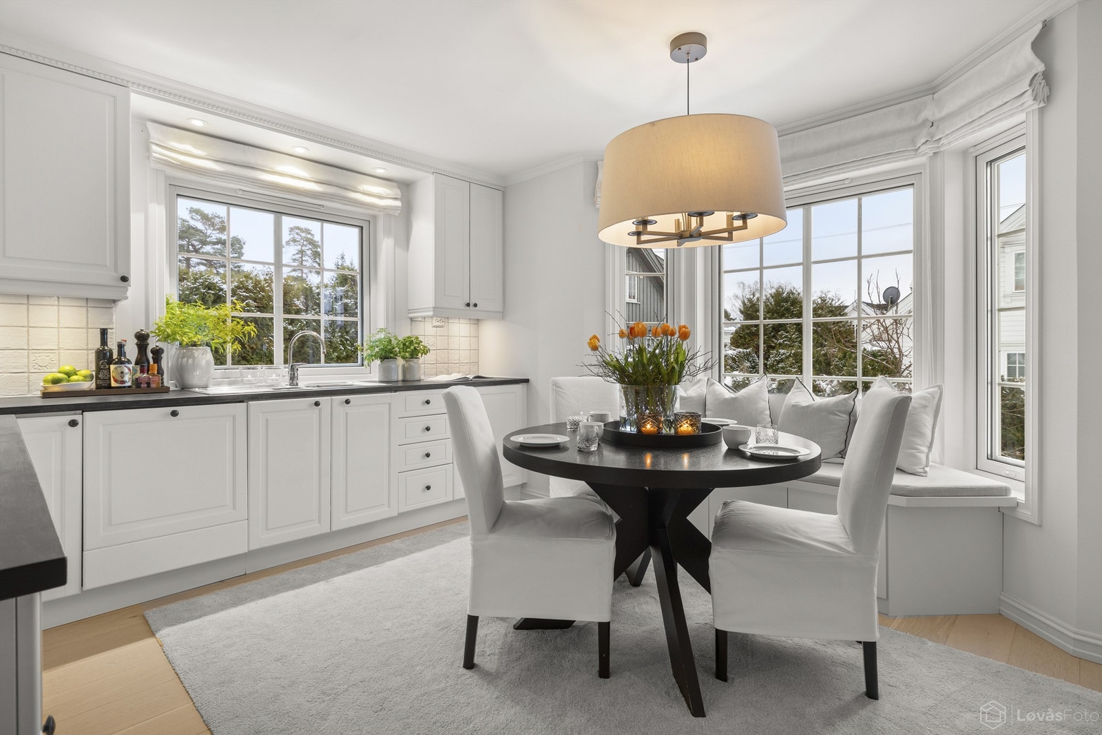 Lyst og koselig kjøkken med plassbygget spiseplass ved karnappet Galleribilde