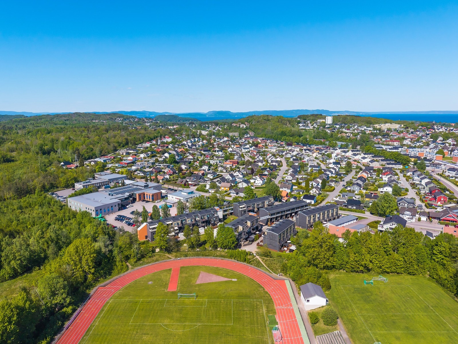Her ser vi et dronebilde av Holtandalen med skogen til venstre og Borre Idrettspark i front Galleribilde