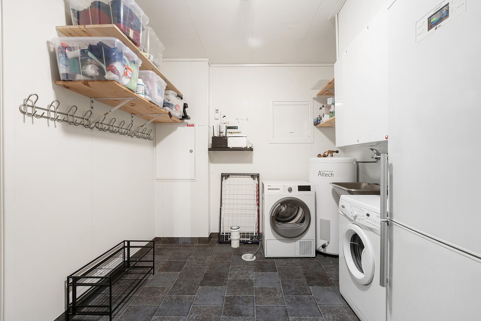 Praktisk vaskerom med opplegg for vaskemaskin, tørketrommel og utslagsvask. Rommet har også gulvvarme. Galleribilde