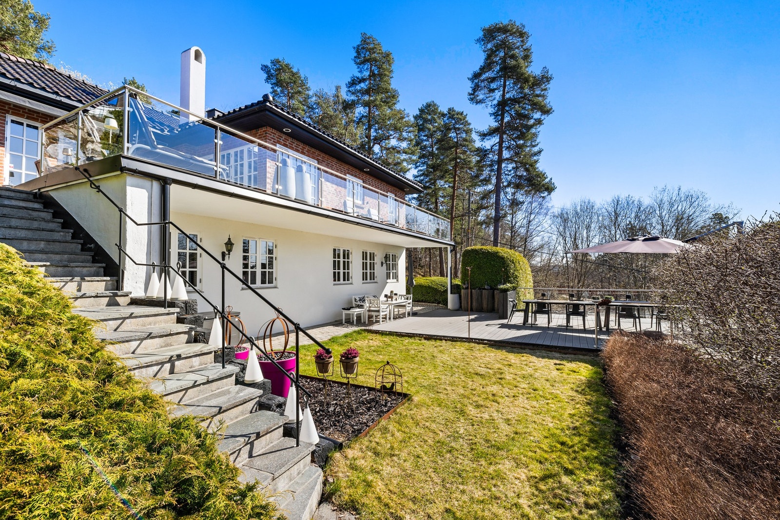 Tomten er vestvendt og skrånende, med pent anlagte plener, prydbusker, bed og naturtomt opp mot bakkant. Galleribilde