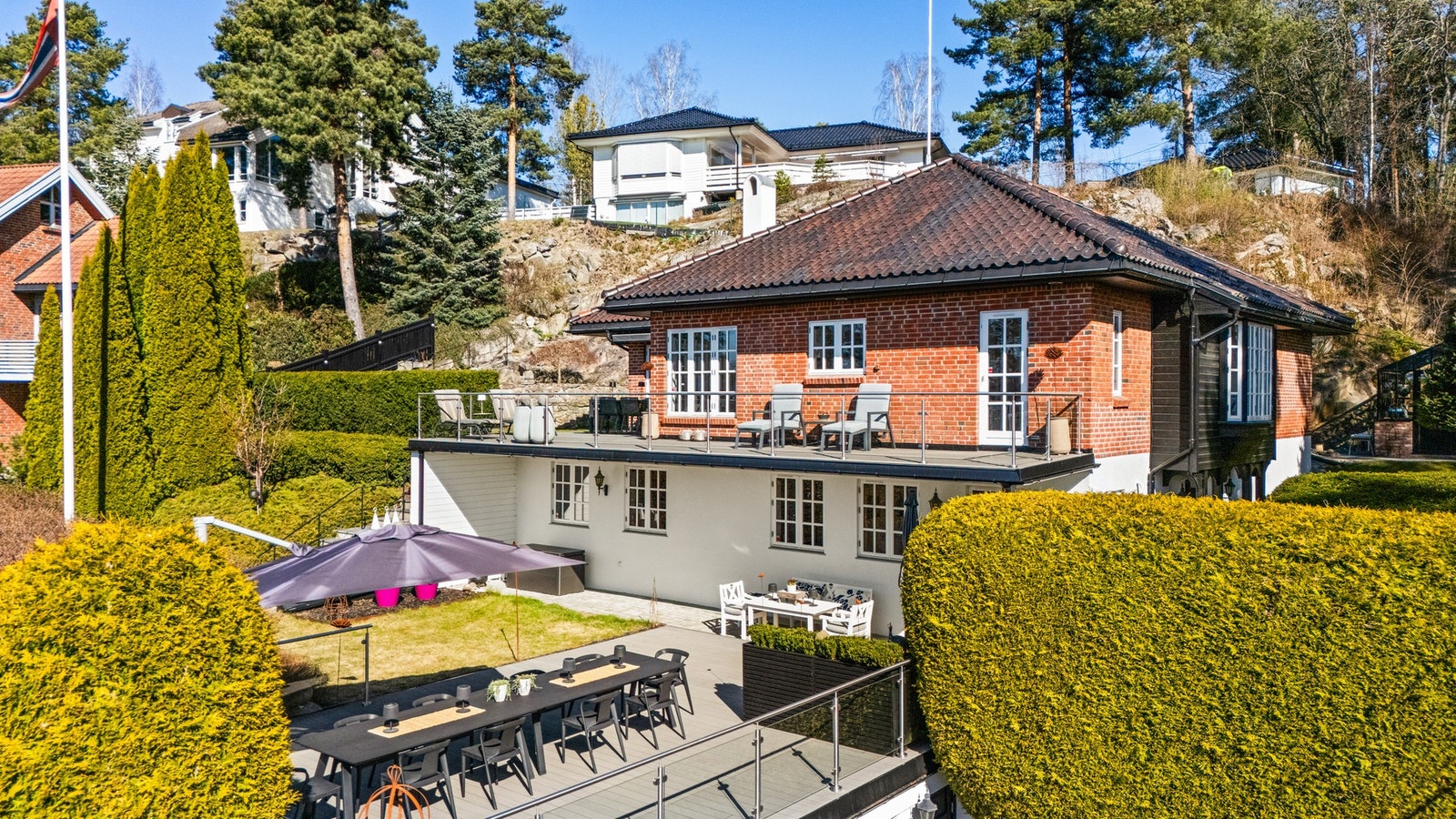 Gårdsplassen er belagt med vakker granittstein og rammes inn av hekk og port, noe som skaper et ryddig og representativt inngangsparti Galleribilde