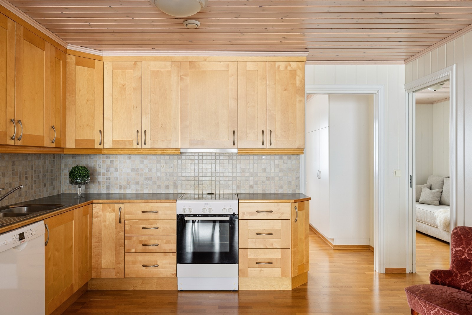 Det er fliser på veggen mellom over- og underskapene, og over komfyren er det tilkoblet en ventilator. Galleribilde