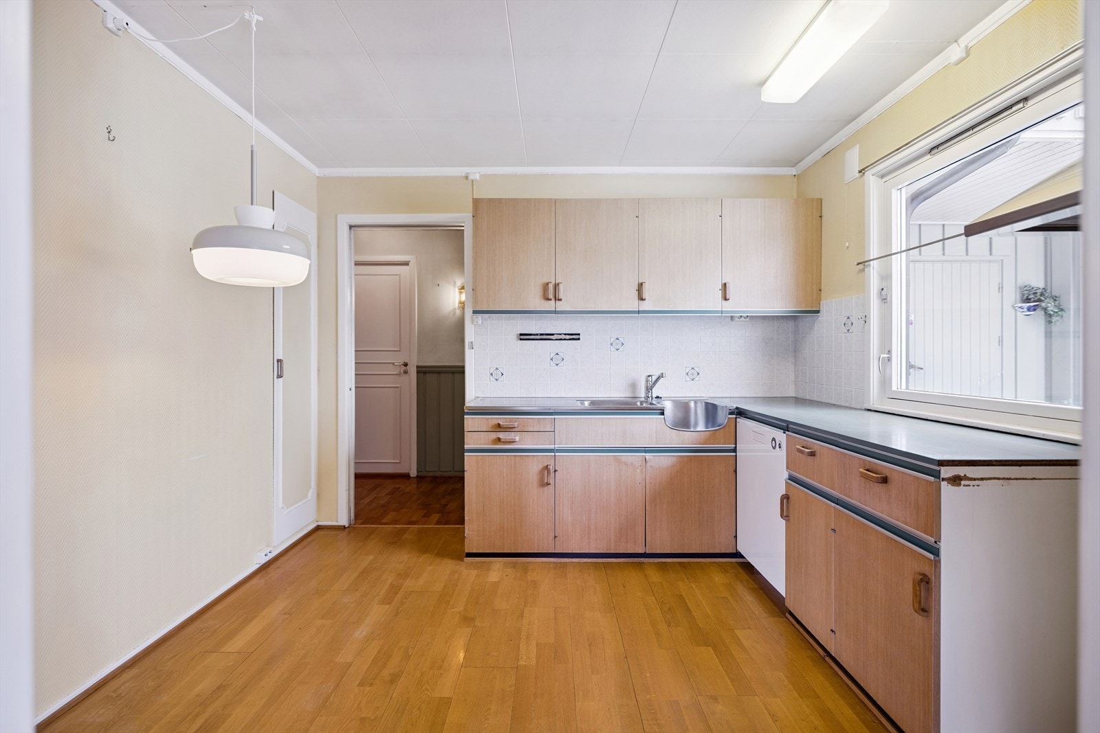 Kjøkken med eldre innredning, laminat benkeplate og flislagt vegg over benk. Galleribilde