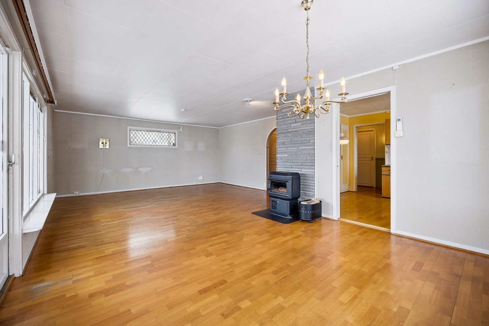 Stue med vedovn som bidrar til oppvarming sammen med elektriske varmekilder. Rommet gir fleksible innredningsmuligheter. Galleribilde