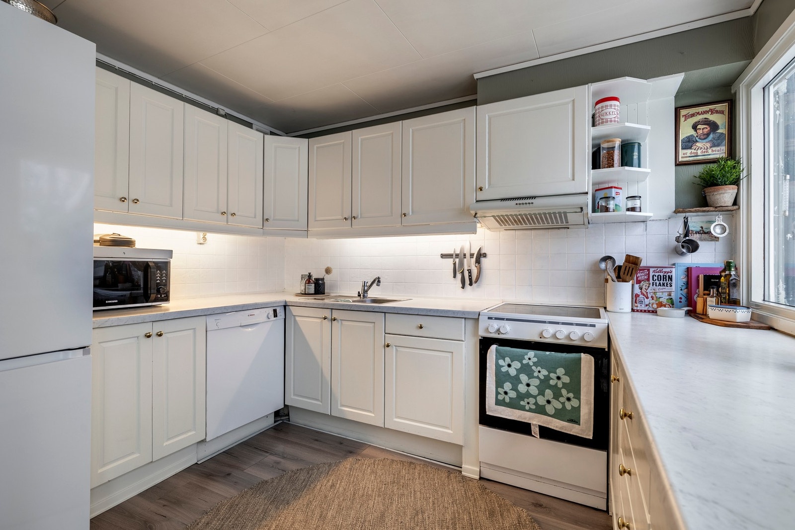 Det er belysning over benken, samt malte fliser på vegg mellom overskap og kjøkkenbenk. Galleribilde