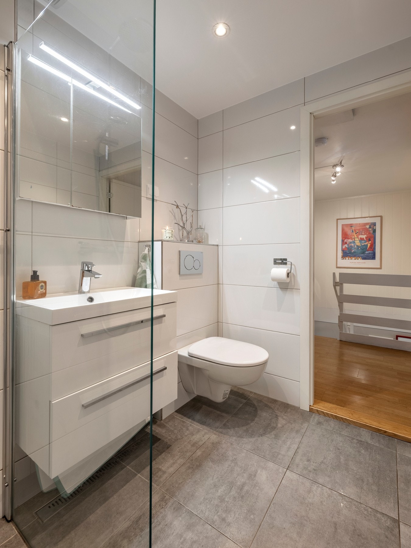 Innredningen består av servantinnredning, speil i dører på overskap over servant, vegghengt toalett og dusjhjørne med glassvegg. Galleribilde