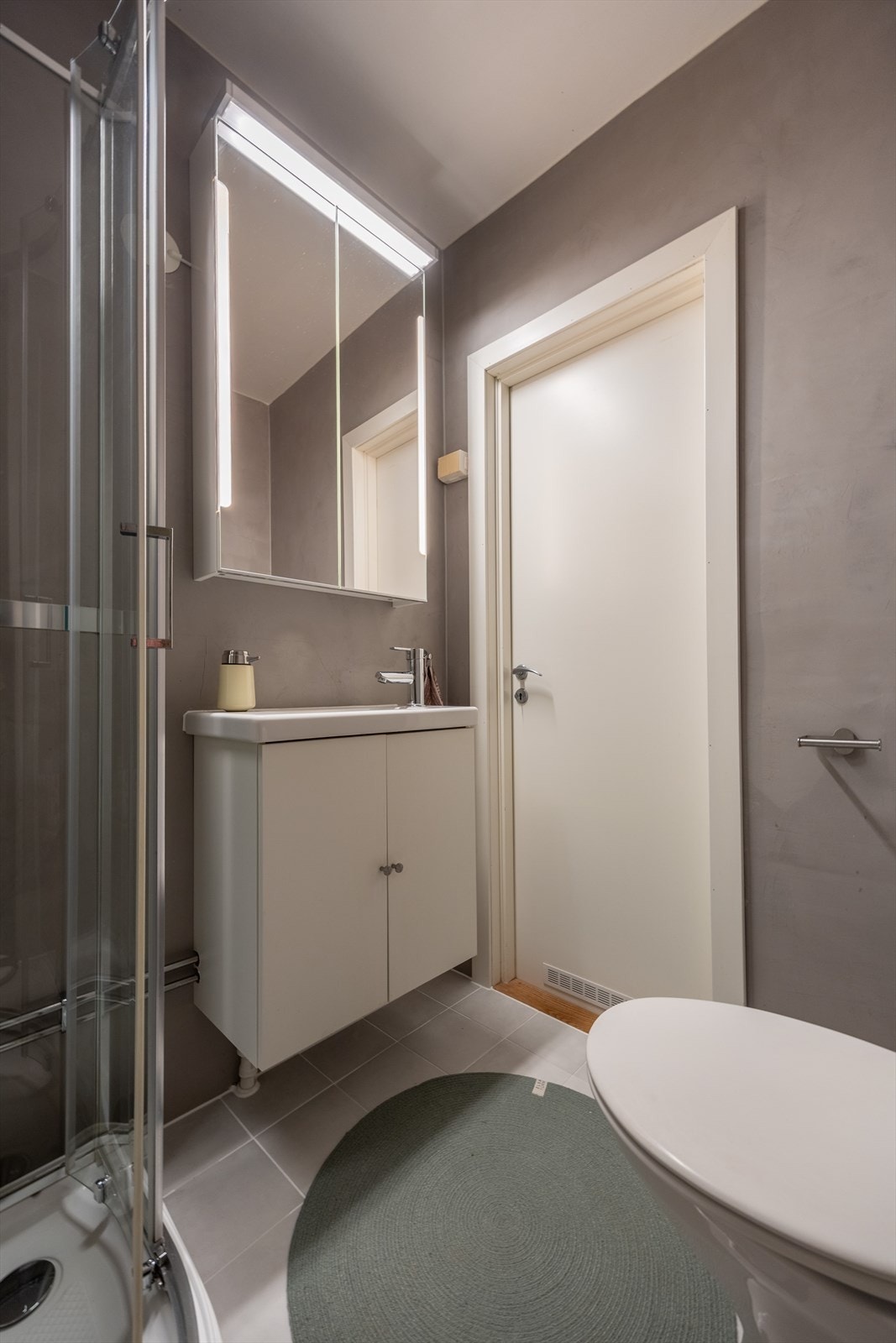 Her er det moderne dusjkabinett, pen baderomsinnredning med vask, overskap med speil og god belysning, WC og opplegg for vaskemaskin. Galleribilde