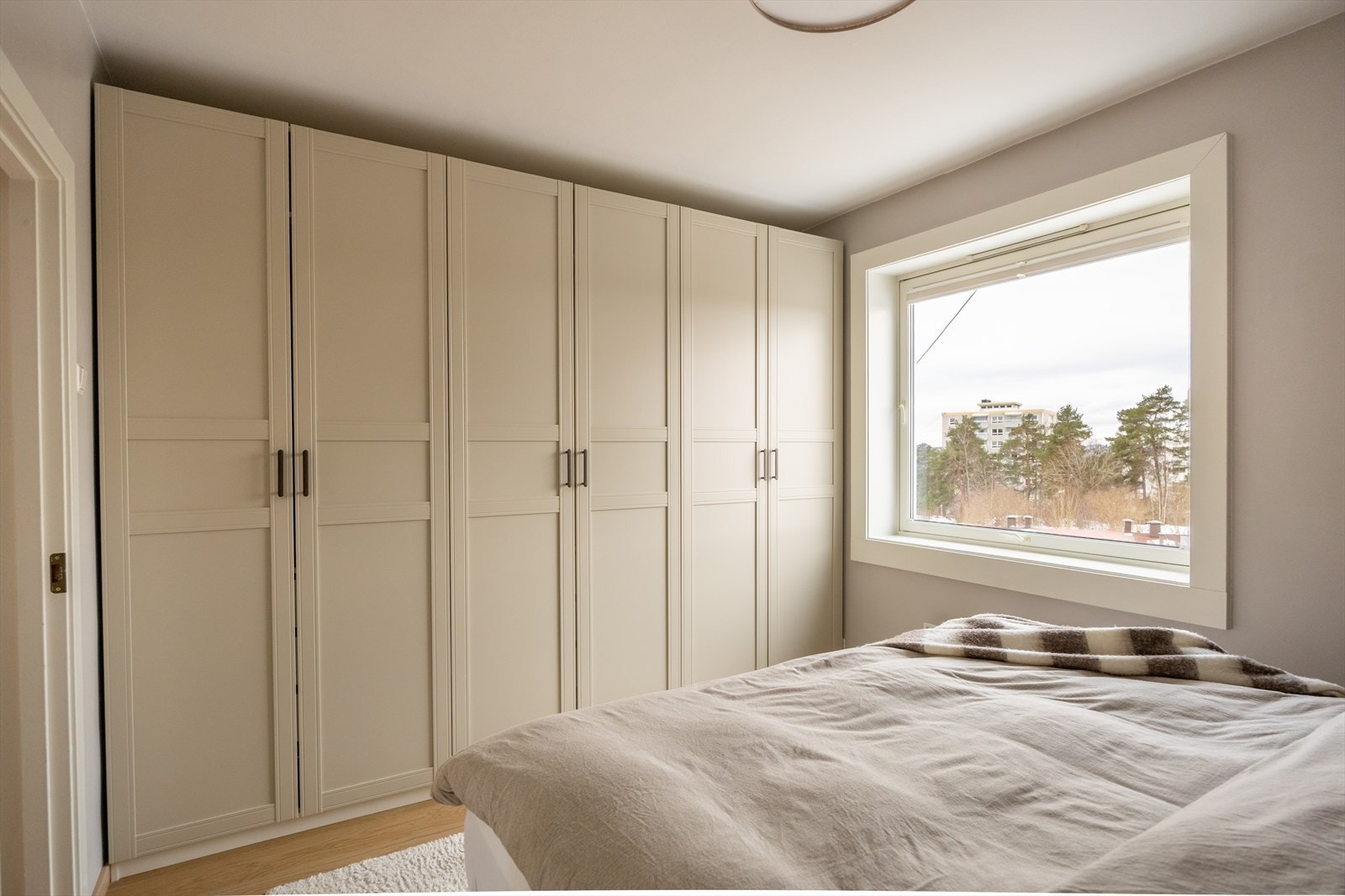 En hel vegg med garderobeskap gir rikelig med oppbevaringsplass. Et stort vindu gir både god utsikt og naturlig lys. En stilren taklampe sørger for godt lys om kvelden. Galleribilde