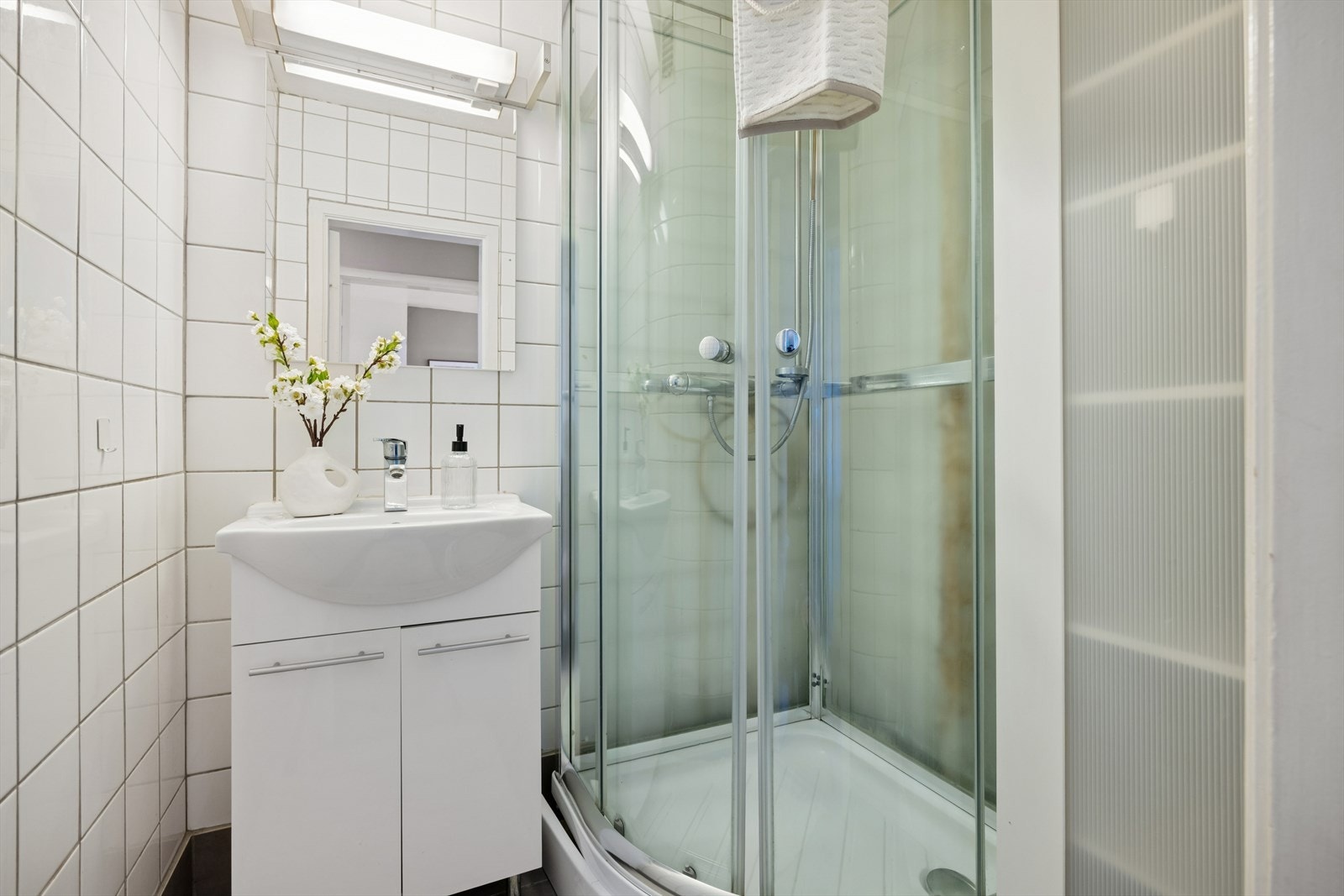 Baderom utstyrt med servant nedfelt i skapinnredning og dusjkabinett. Galleribilde