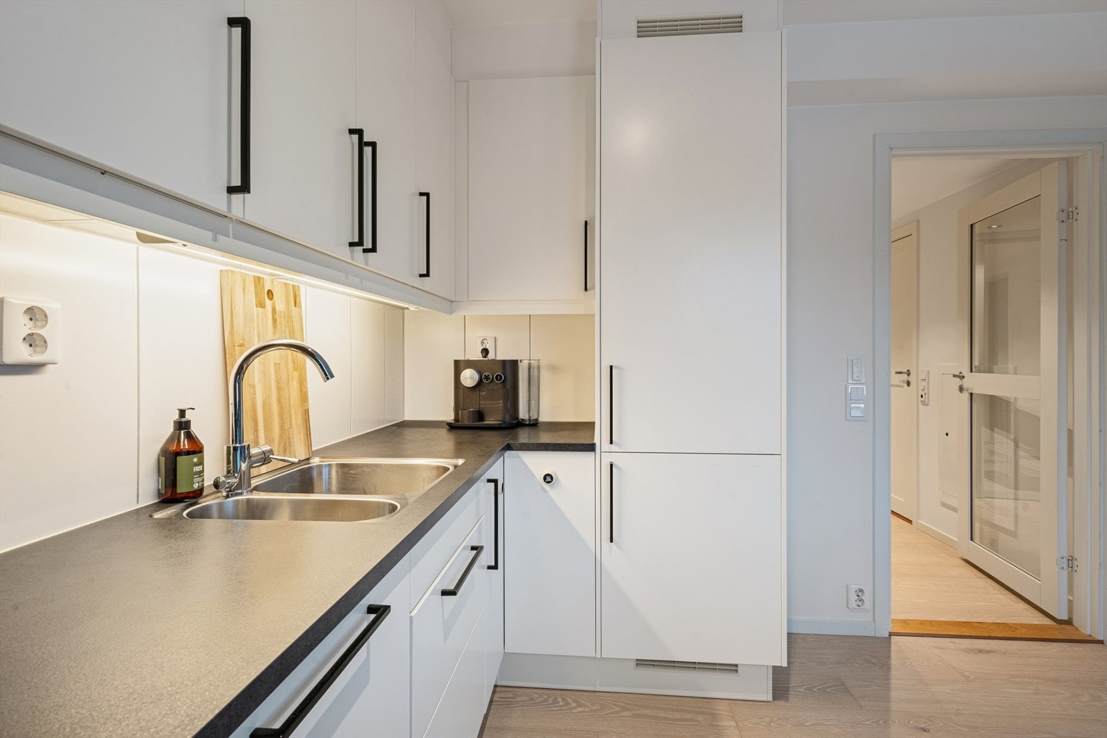 Innredningen har glatte fronter som gir et tidløst uttrykk, kombinert med laminat benkeplate og nedfelt kum i rustfritt stål. Galleribilde