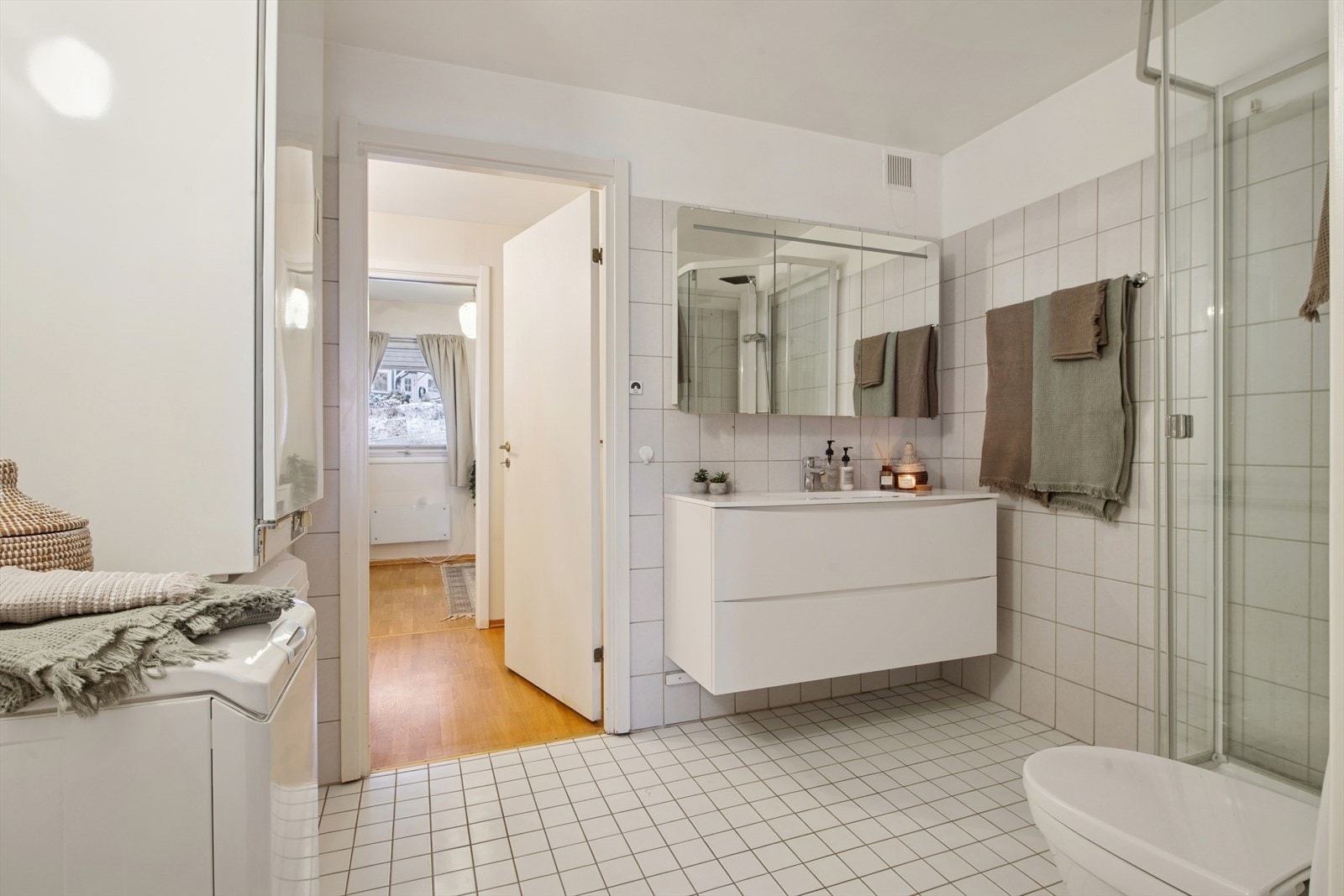 Det store baderommet består av hvite fliser på vegger og gulv, og har behagelig gulvvarme. Galleribilde