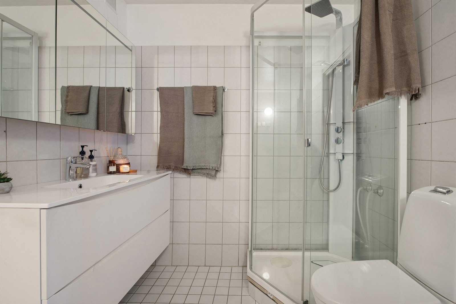 Rommet er innredet med servant med skuffer under og speilbelagt skap over, dusjkabinett, WC, vaskemaskin og tørkeskap. Galleribilde