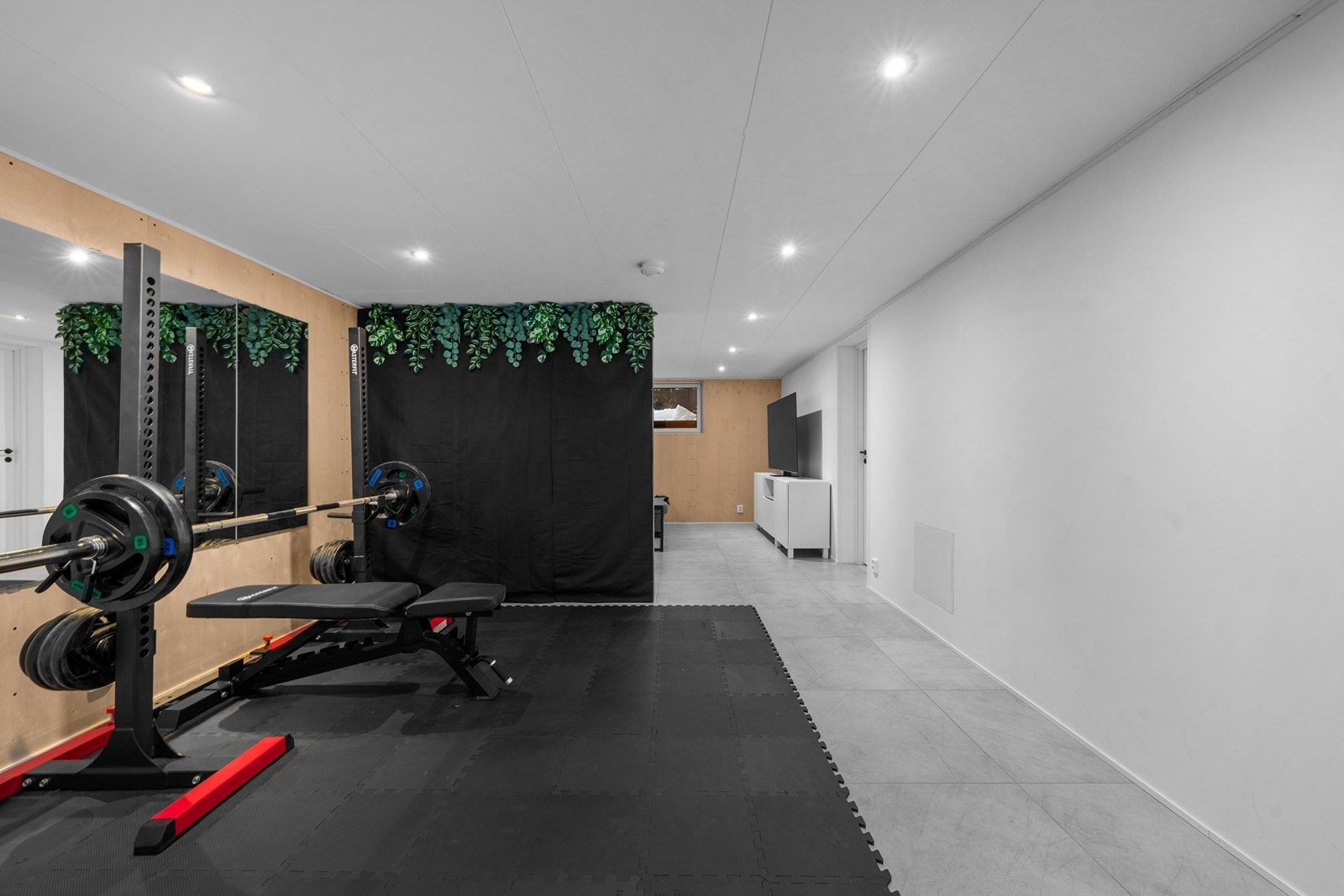 Romslig kjellerstue som i dag brukes til både treningsrom og TV-stue Galleribilde