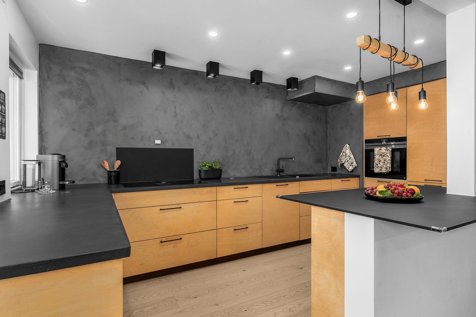 Pent kjøkken med integrerte hvitevarer, sorte detaljer og brytningsvegg med kalkmaling. Galleribilde