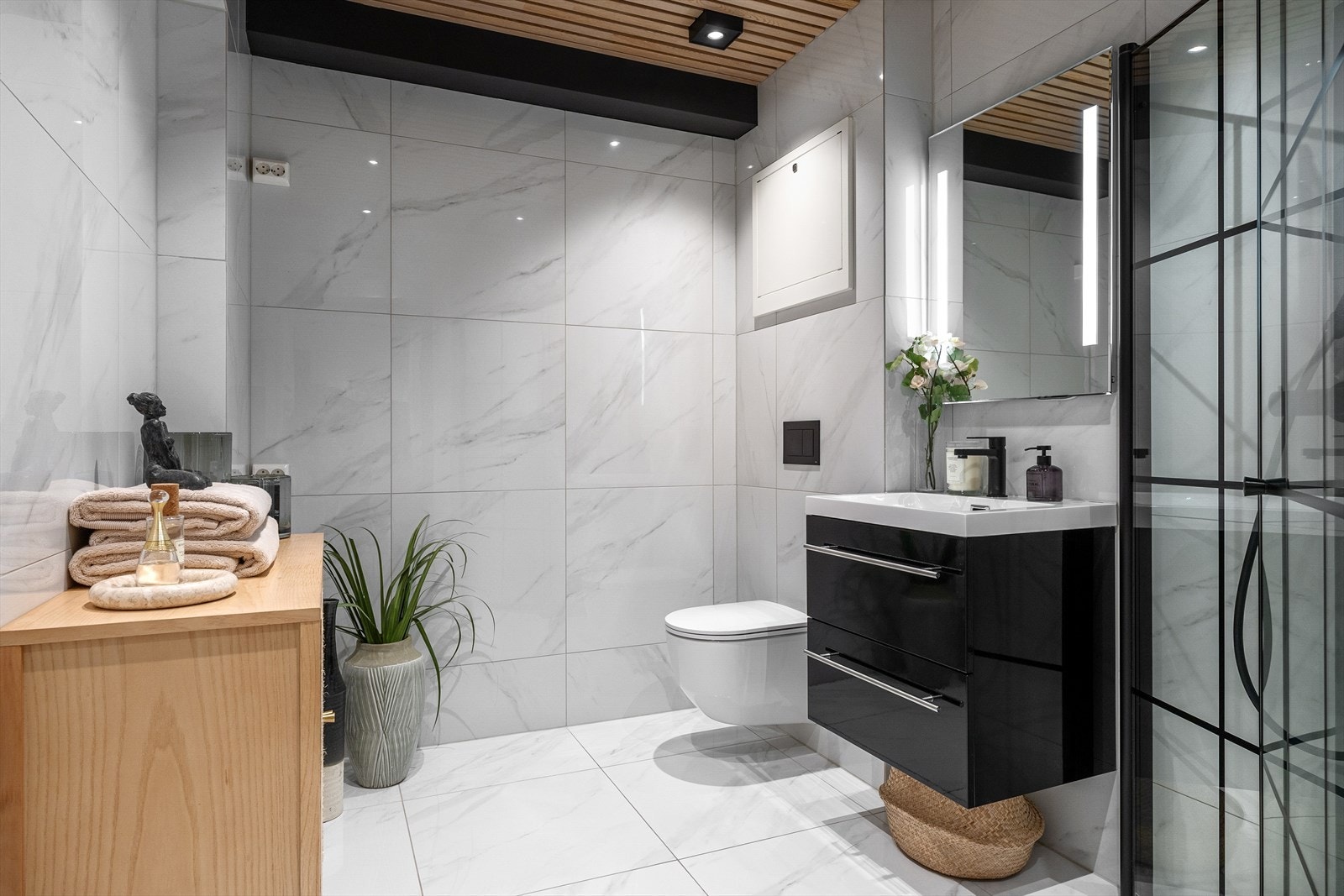 Romslig og delikat bad fra 2022 med store marmorerte fliser på gulv og vegger. Det er også opplegg for vaskemaskin og tørketrommel. Galleribilde