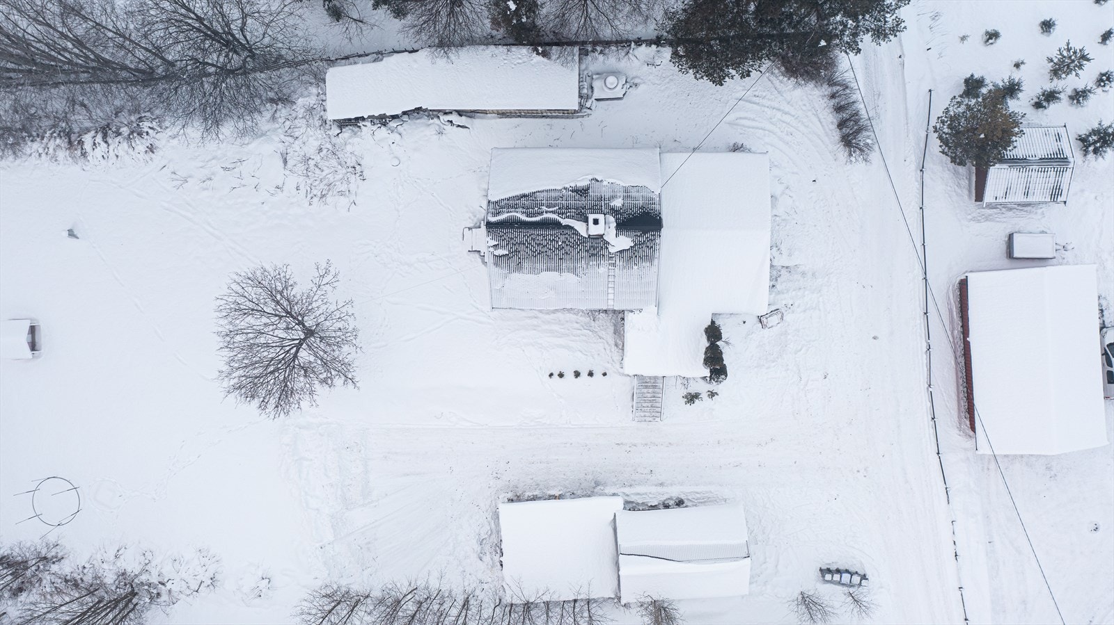 Luftfoto av eiendommen viser eneboligen med tilhørende garasje og snødekte omgivelser. Galleribilde