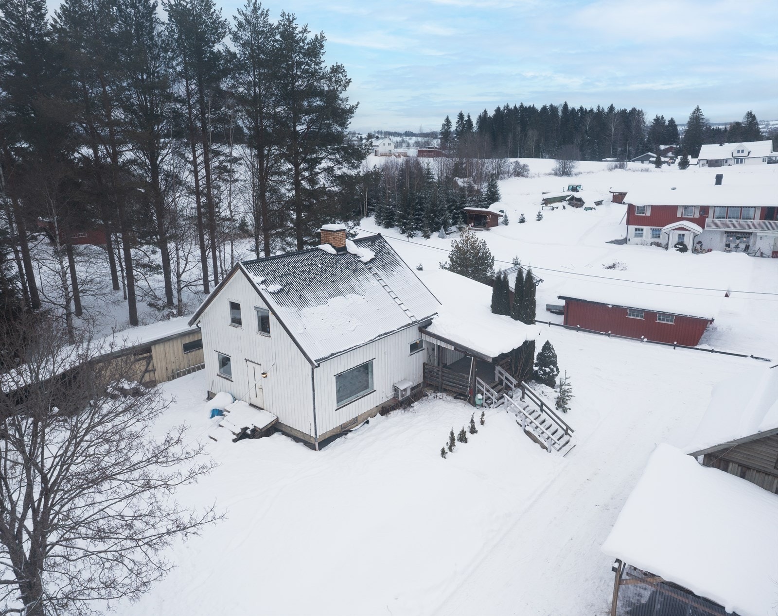 Oversiktsbilde viser eiendommen med enebolig og garasje, omgitt av snødekt landskap. Galleribilde