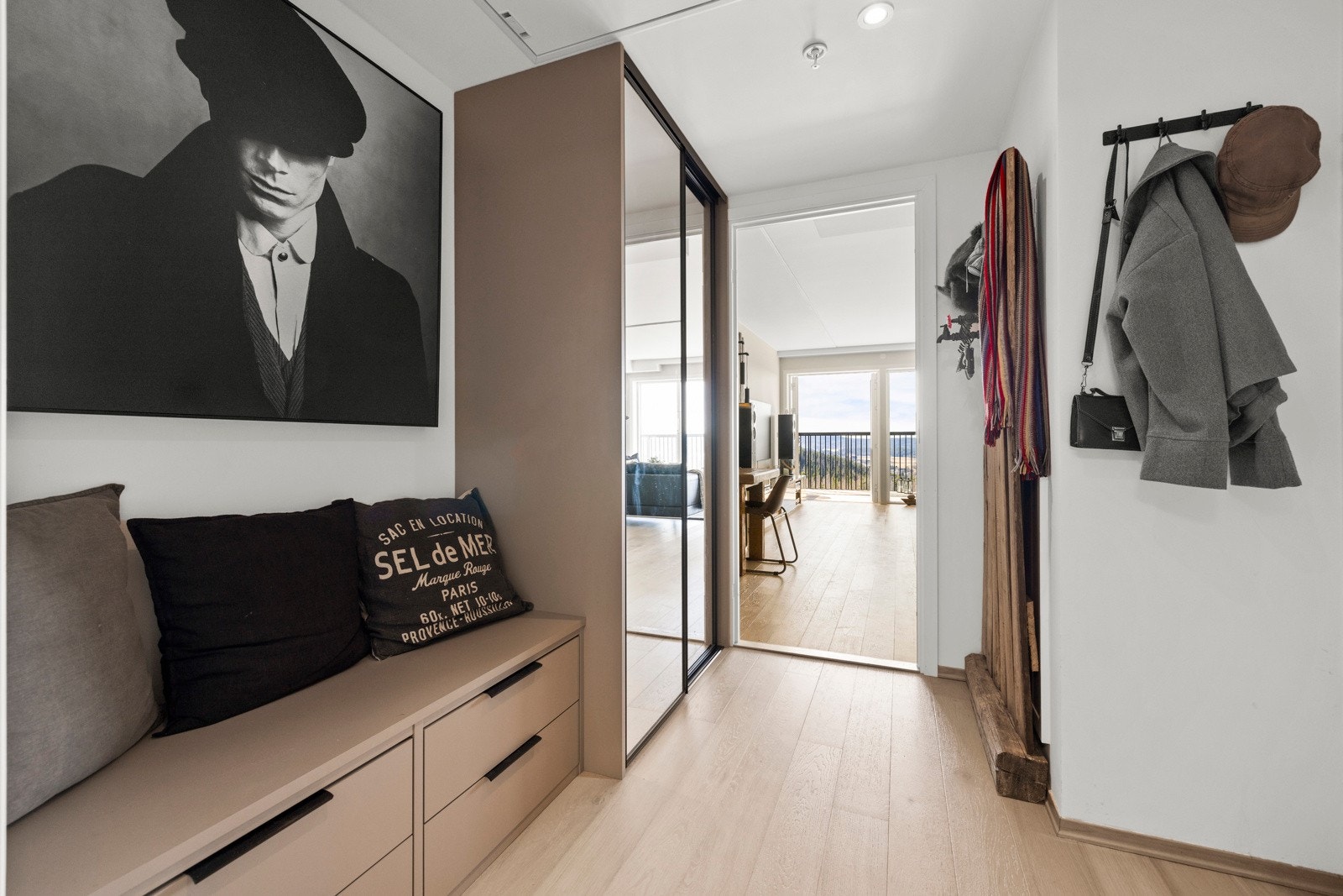 Entré/gangen gir et godt førsteinntrykk av leiligheten. Gangen har en praktisk skyvedørsgarderobe fra Acme for oppbevaring av ytterklær. Det er også en sittebenk med skuffer under i samme stil. Galleribilde