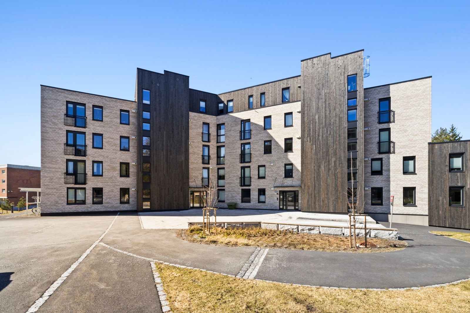 Fasade/fellesområde. Borettlaget har et pent opparbeidet fellesområde med blant annet sittebenker og en lekeplass. Galleribilde