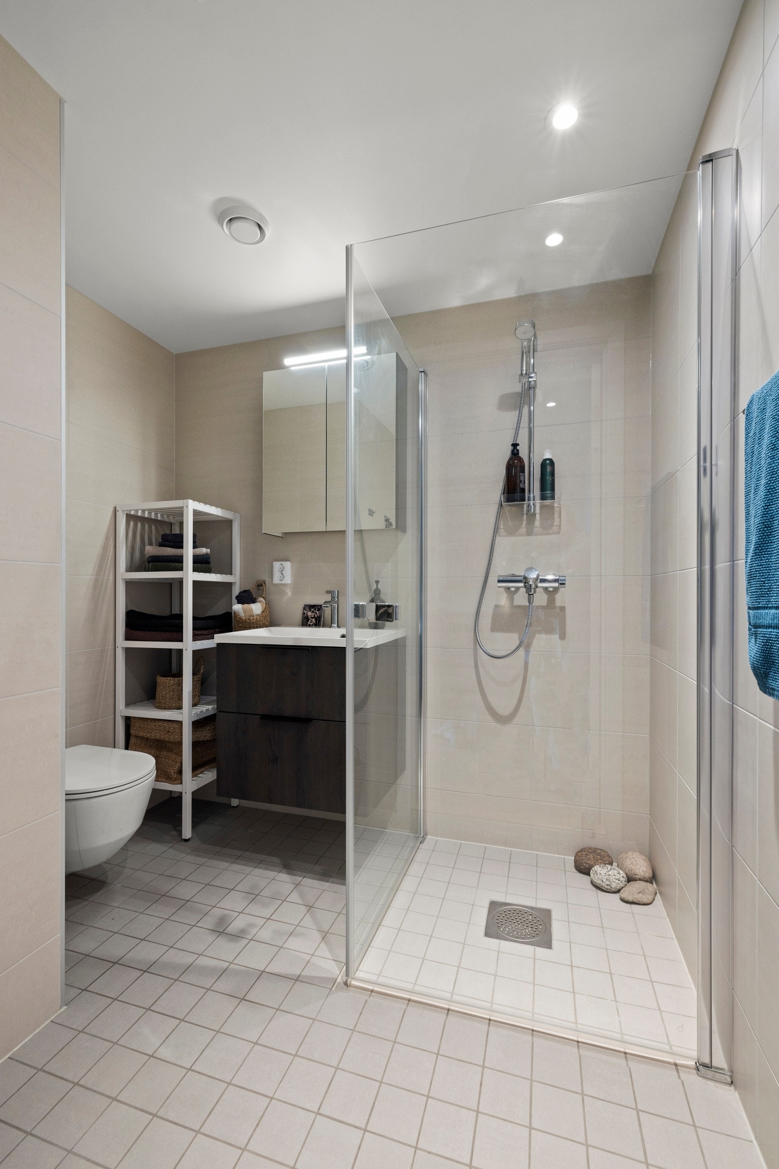 På bad 1 er det et veggmontert toalett, dusjdører i herdet glass, speilskap med overliggende belysning, baderomsinnredning med finerte fronter og heldekkende servant. Galleribilde