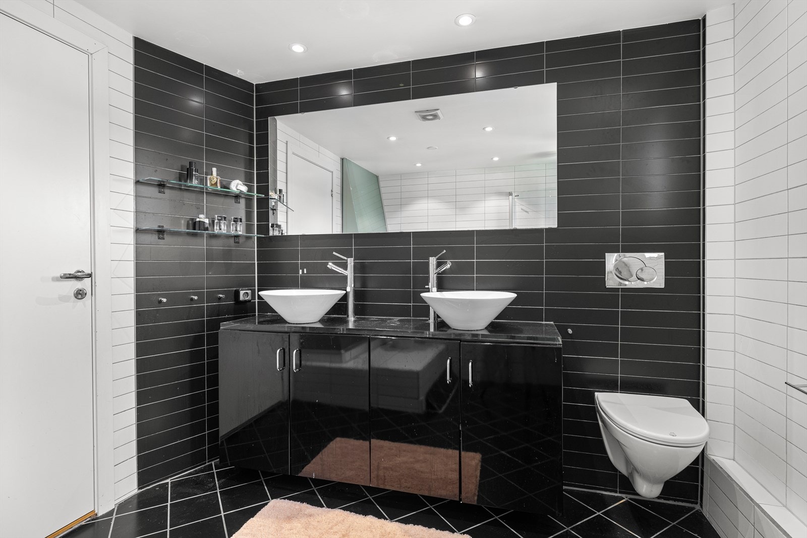 Rommet er innredet med vegghengt toalett og servantløsning med sorte høyglansfronter, benkeplate i pleksiglass/akryl, to servanter og tilhørende ettgrepsarmatur. Galleribilde