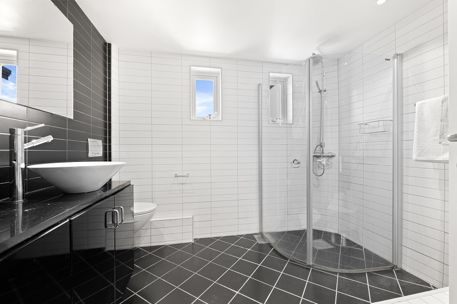 Pent, flislagt baderom med gulvvarme og downlights i himlingen. Dusjhjørnet er rett på gulv med innfellbare glassdører, utstyrt med dusjbatteri, regndusj og hånddusj for økt komfort. Galleribilde