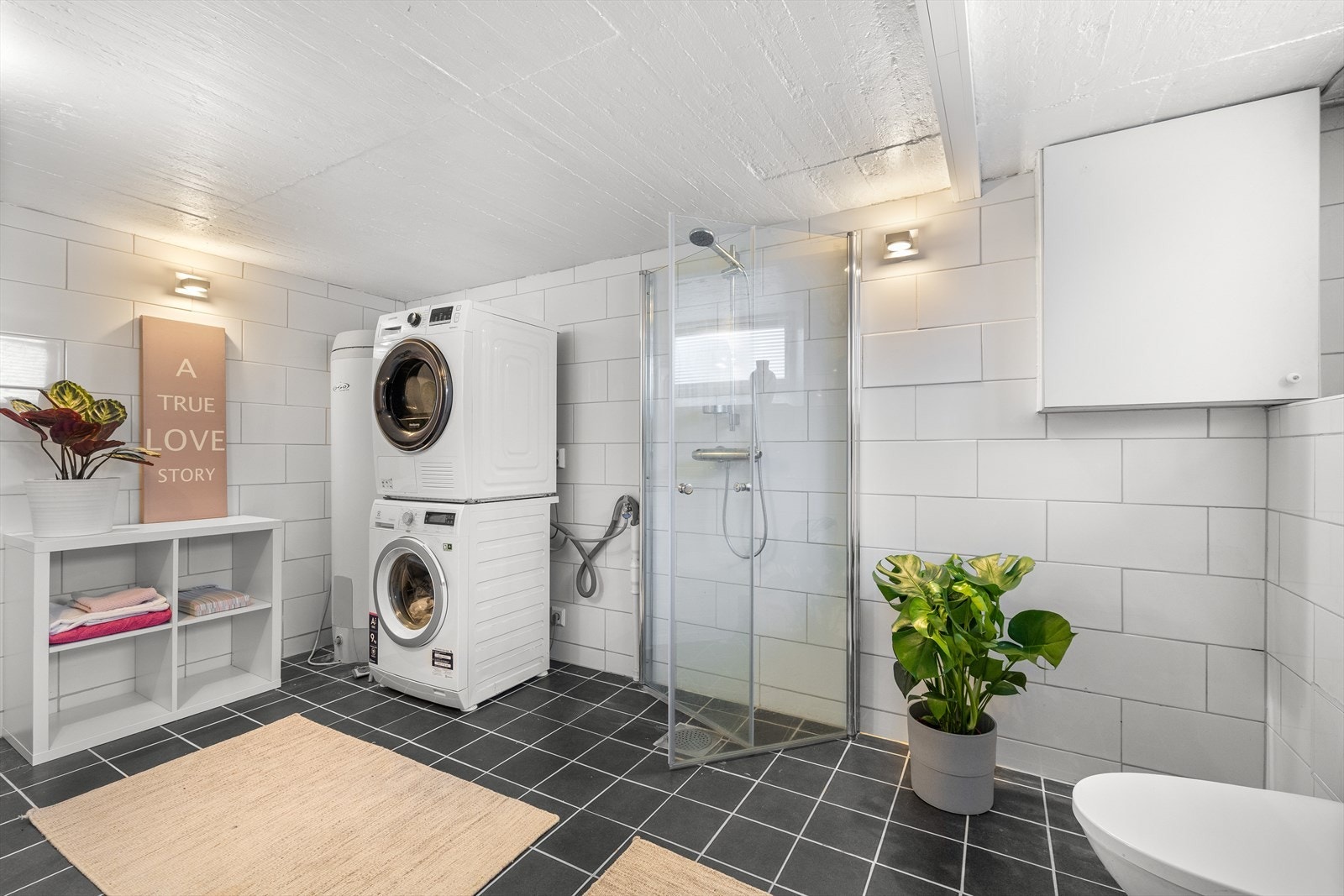 Romslig, flislagt vaskerom/baderom fra 2014 med gulvvarme. Rommet er utstyrt med vegghengt toalett, servantinnredning med hvite, glatte fronter, heldekkende servant, ettgrepsarmatur samt speil med belysning. Galleribilde