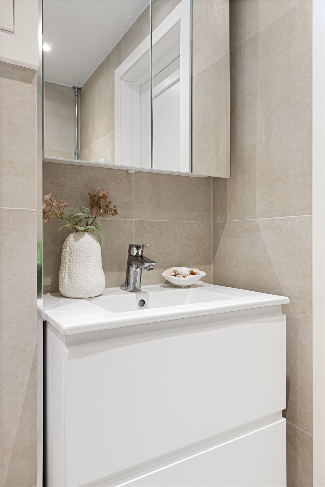 Badet er innredet med servant, dusj med innfellbare dører i herdet glass, veggfestet klosett med innebygget sisterne og opplegg for vaskemaskin Galleribilde