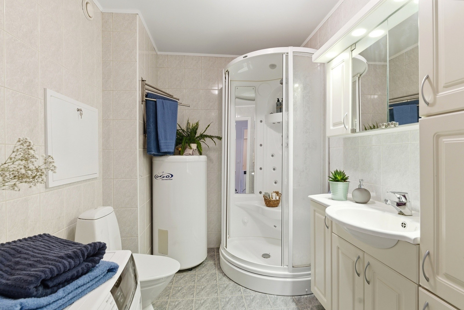 Flislagt bad med varmekabler i gulvet. Badet har innredning med nedfelt servant, toalett, dusjkabinett og opplegg for vaskemaskin. Galleribilde