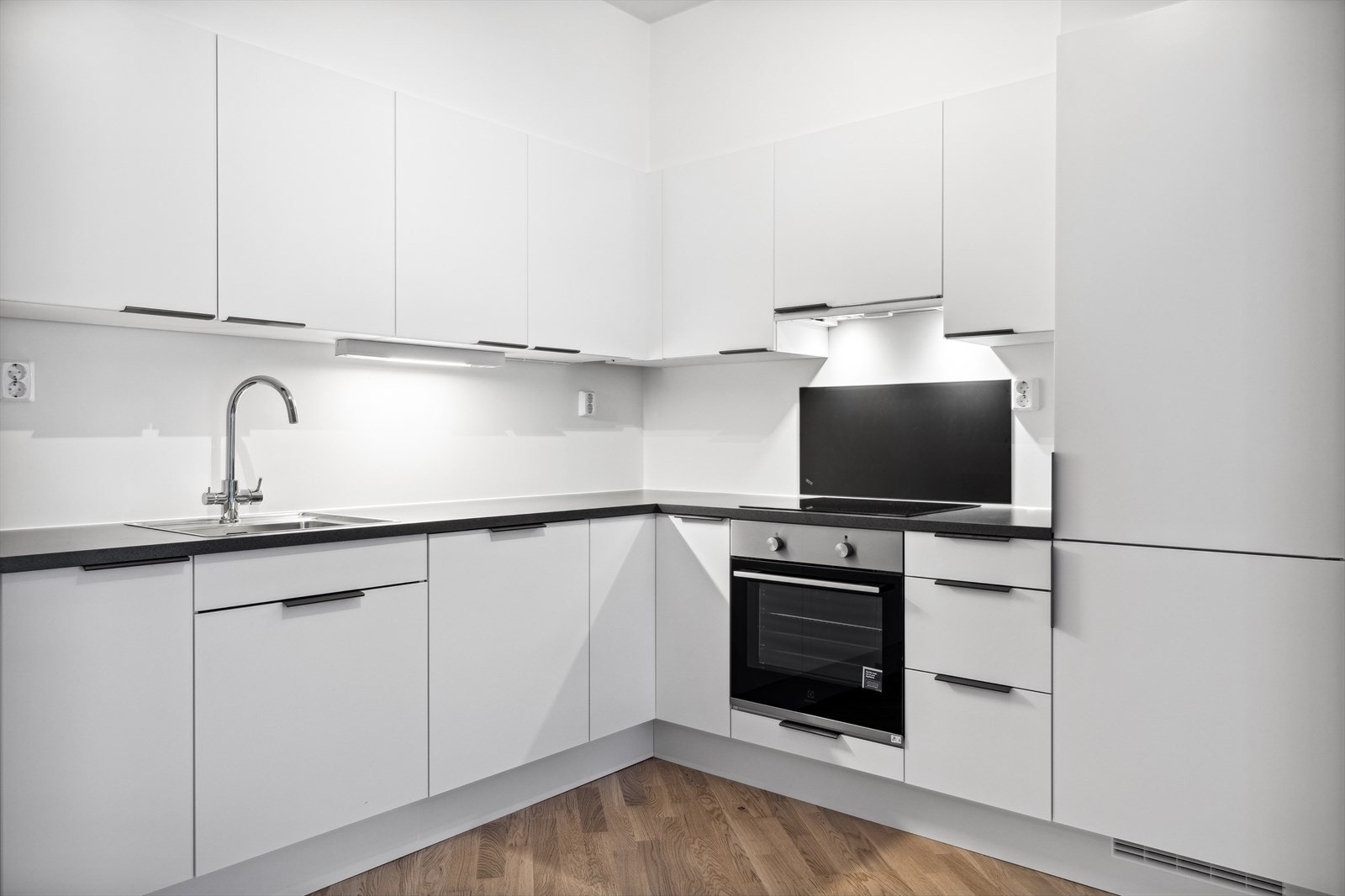 Moderne kjøkken med takhøy innredning, laminatbenkeplate og integrerte hvitevarer. Galleribilde