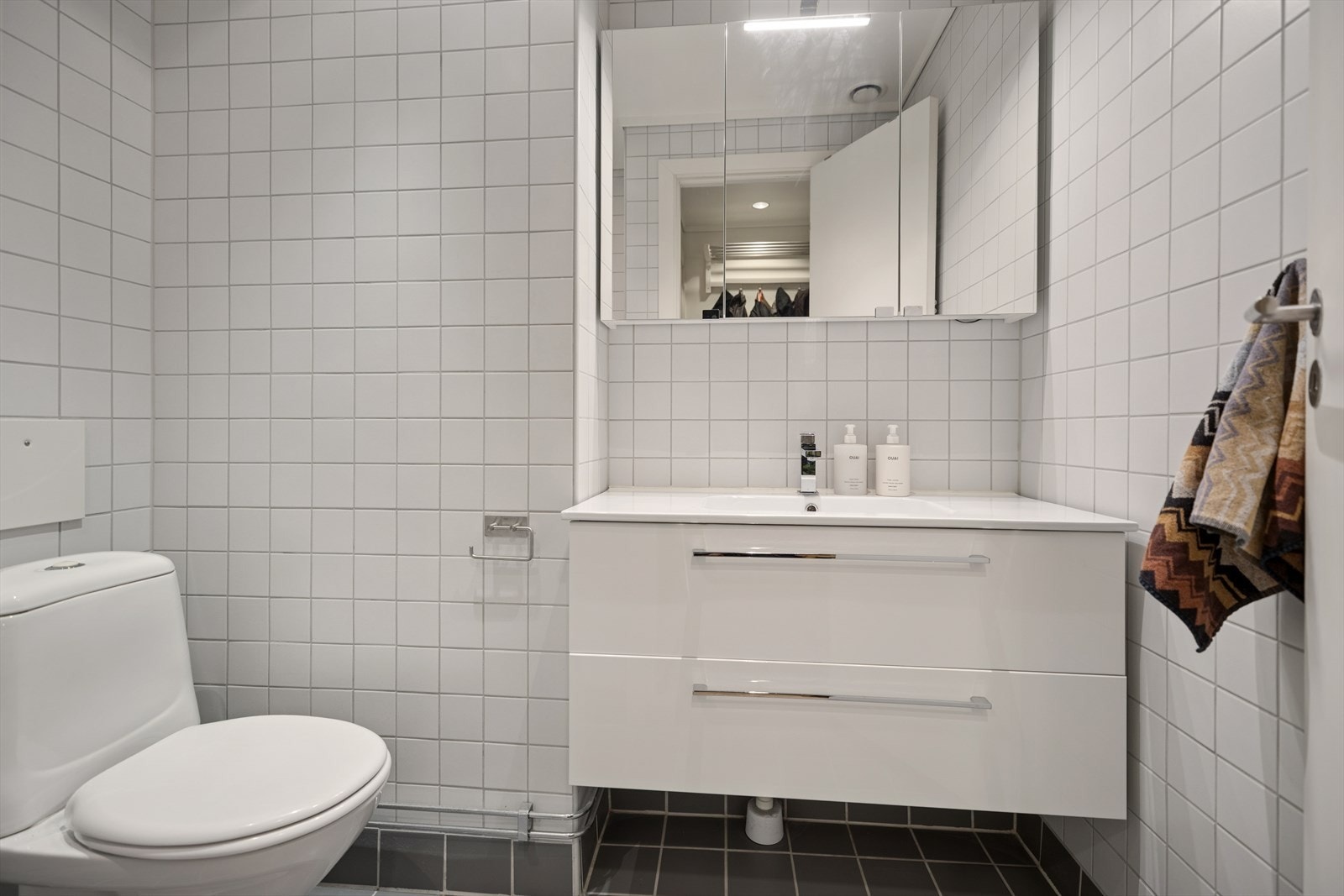 Moderne bad med flislagte vegger og gulv, gulvvarme, og lys innredning med glatte fronter Galleribilde