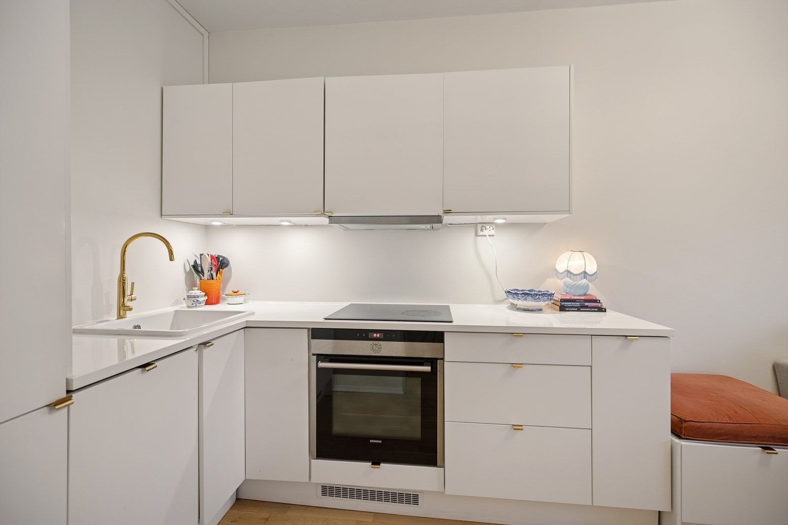 Kjøkkenet fremstår moderne og funksjonelt med glatte fronter, integrerte hvitevarer og praktisk belysning under overskapene Galleribilde