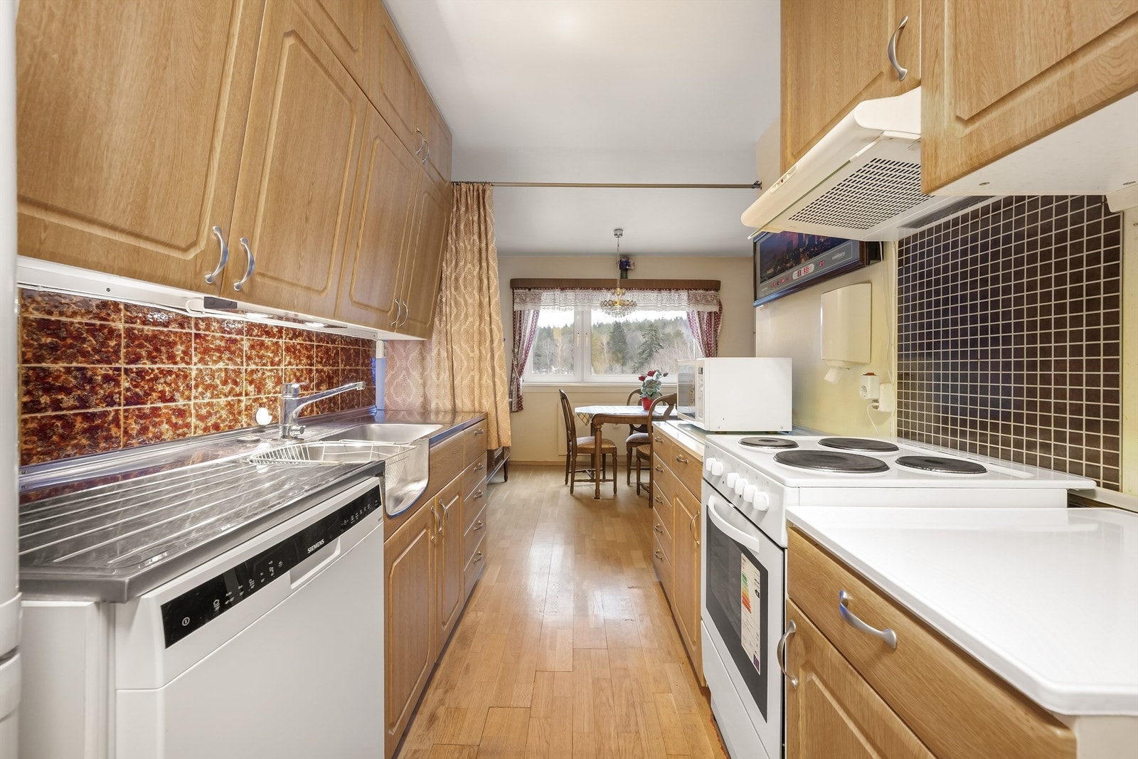 Eldre kjøkkeninnredning med profilerte fronter. Stålbeslag med med nedfelt vask- og skyllekum, samt laminat benkeplate. Galleribilde