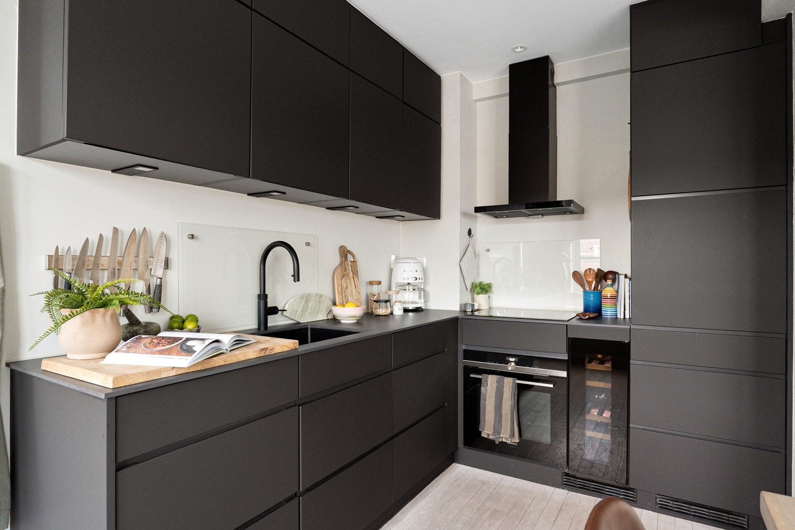 Kjøkkenet er stilrent med slette fronter og en slitesterk, keramisk benkeplate Galleribilde