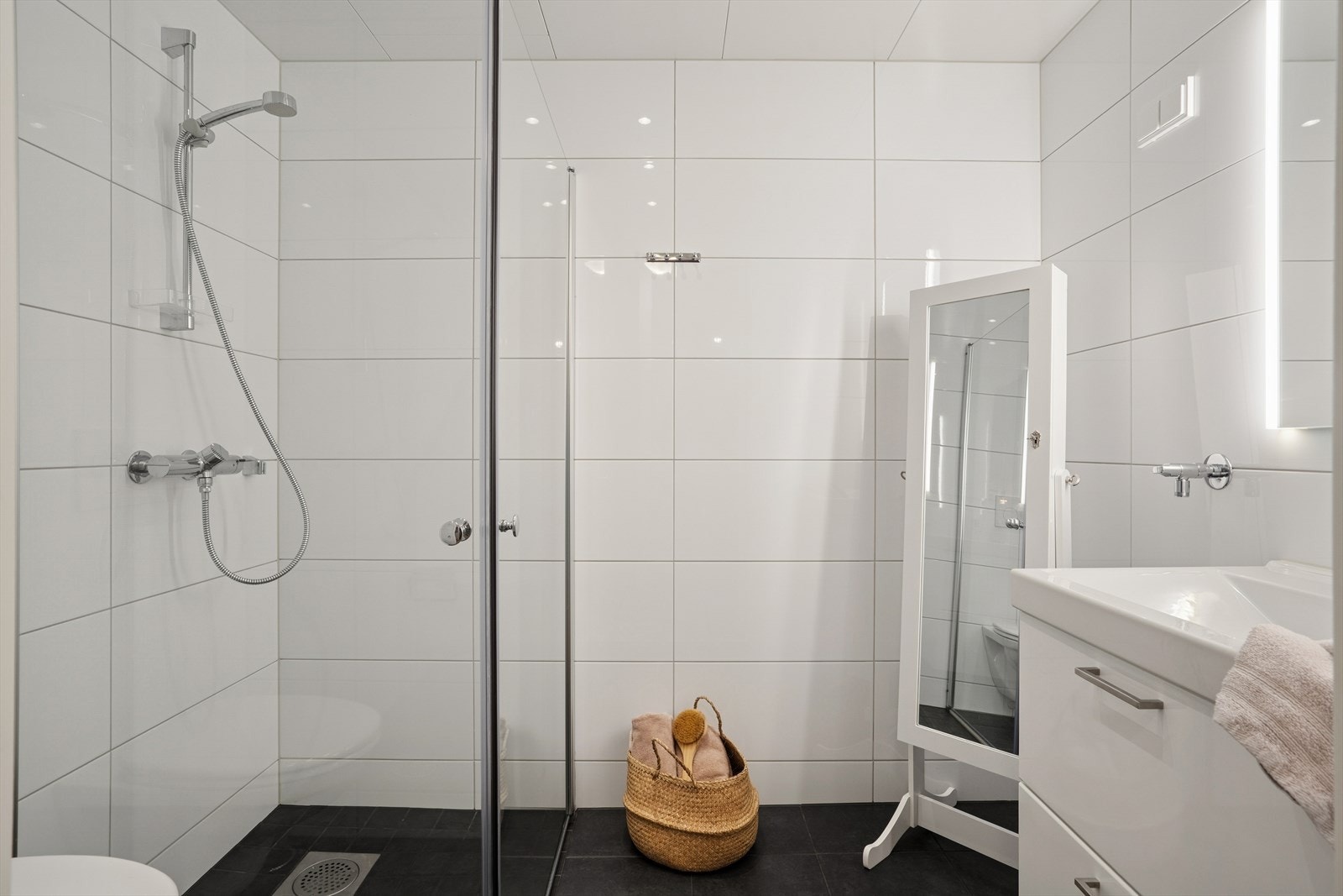 Badet er helfliset med grå fliser på gulvet og hvite fliser på vegg. Også her har man varmekabler i gulvet. Badet er ellers utstyrt med dusjhjørne, vegghengt toalett og baderomsinnredning med nedfelt servant. Avtrekk via balansert ventilasjon. Galleribilde