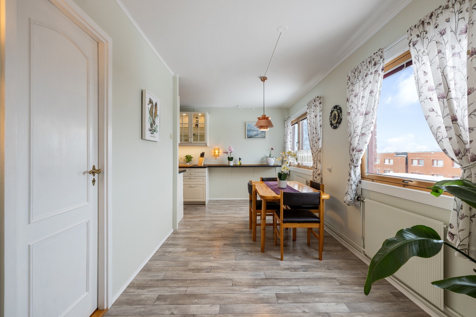 En stor spiseplass får en naturlig plassering ved kjøkkenet foran de store vindusflatene ut mot den fredelige balkongsiden Galleribilde