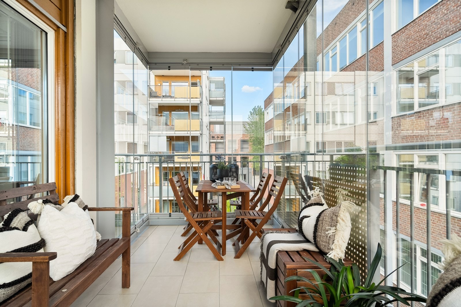 Flislagt gulv gir et stilrent og lettstelt uttrykk, og de skyvbare glassfeltene gjør det enkelt å tilpasse etter vær og sesong. Galleribilde