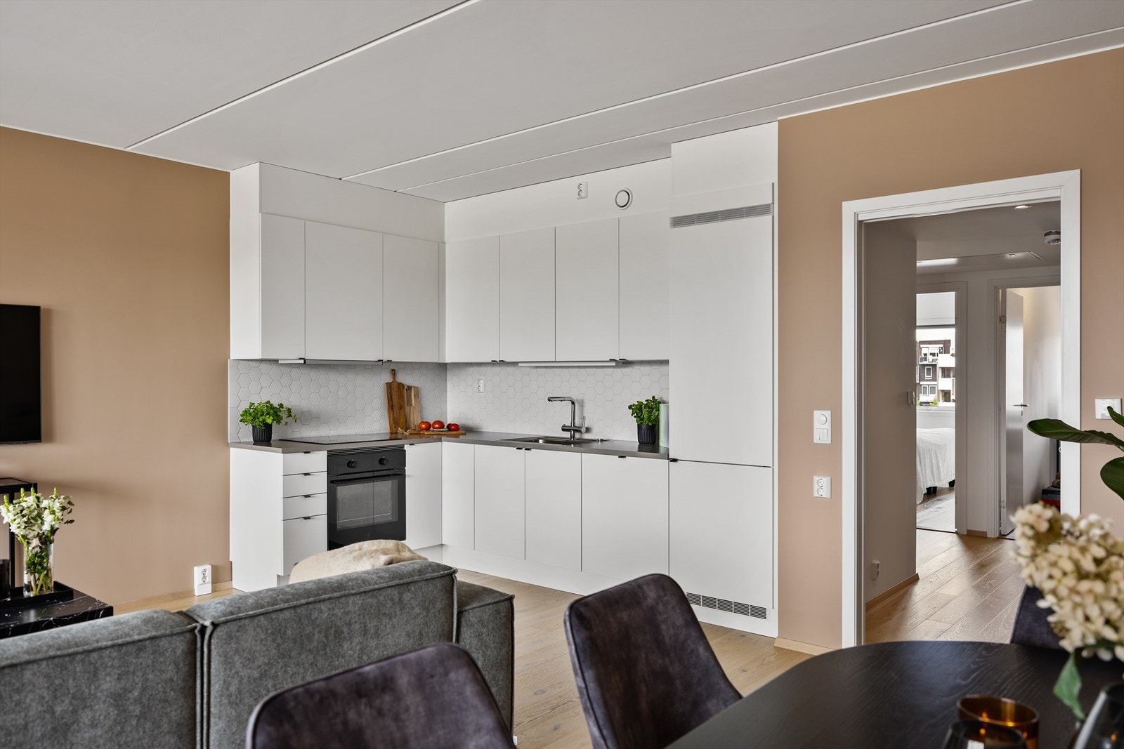 Kjøkkeninnredningen har hvite slette fronter og laminerte benkeplater. Flotte heksagonfliser pryder og beskytter bakveggene. Galleribilde