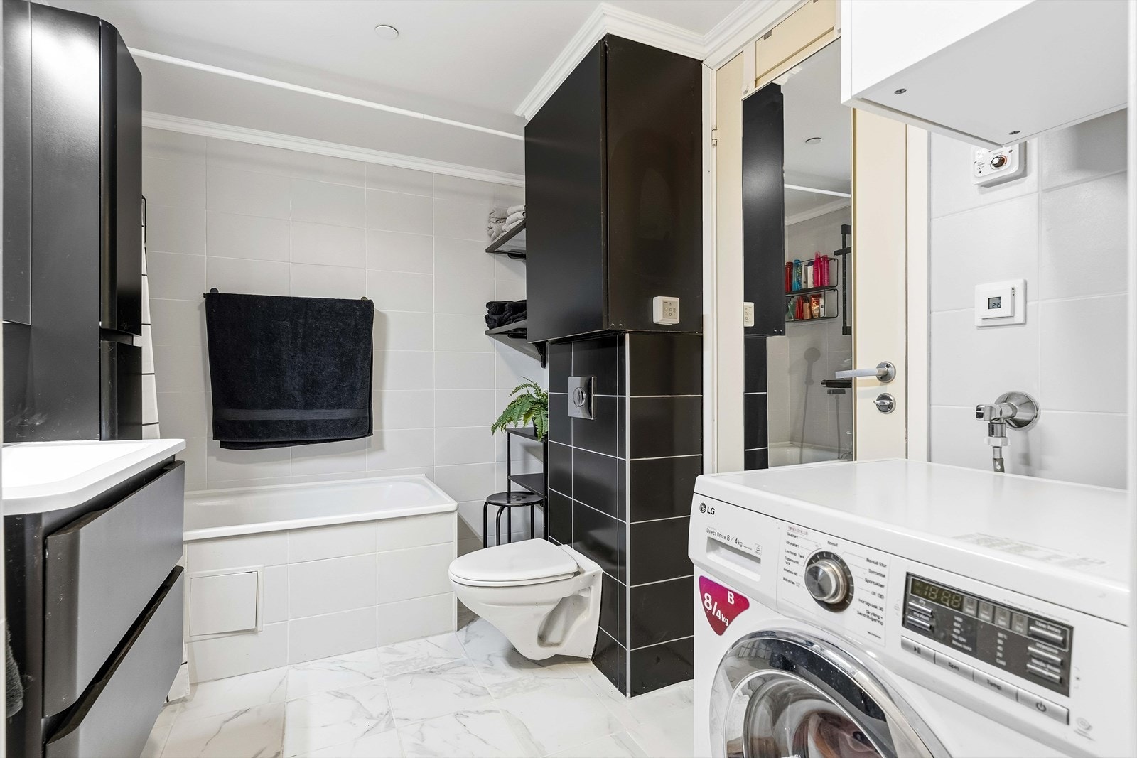 Badekar med dusjløsning og plass til vaskemaskin gjør rommet svært funksjonelt. Galleribilde