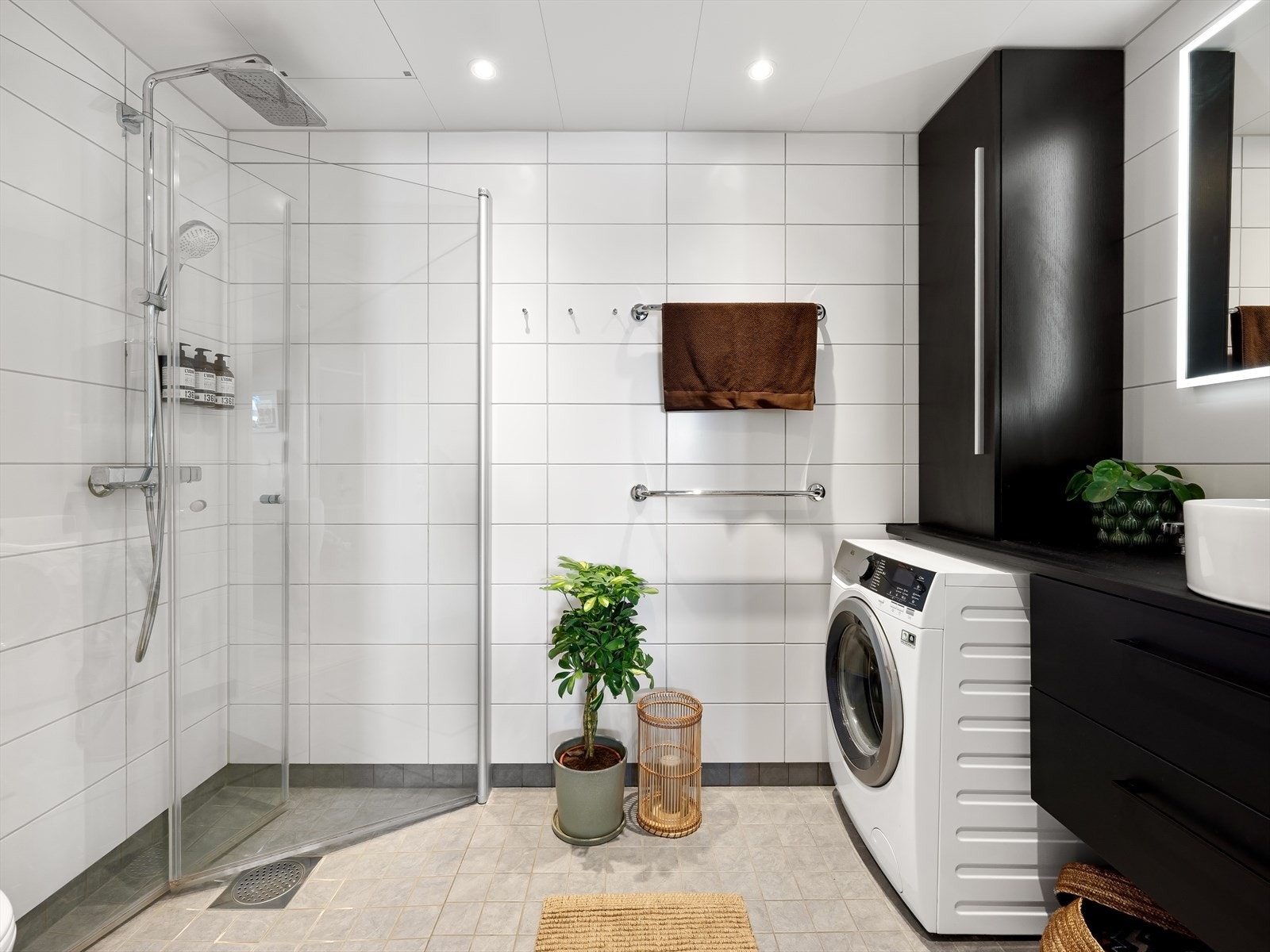 Hovedbad som er flislagt med varmekabler, benkeskap og veggskap med glatte fronter og dusj med innfellbare dører i herdet glass. Galleribilde