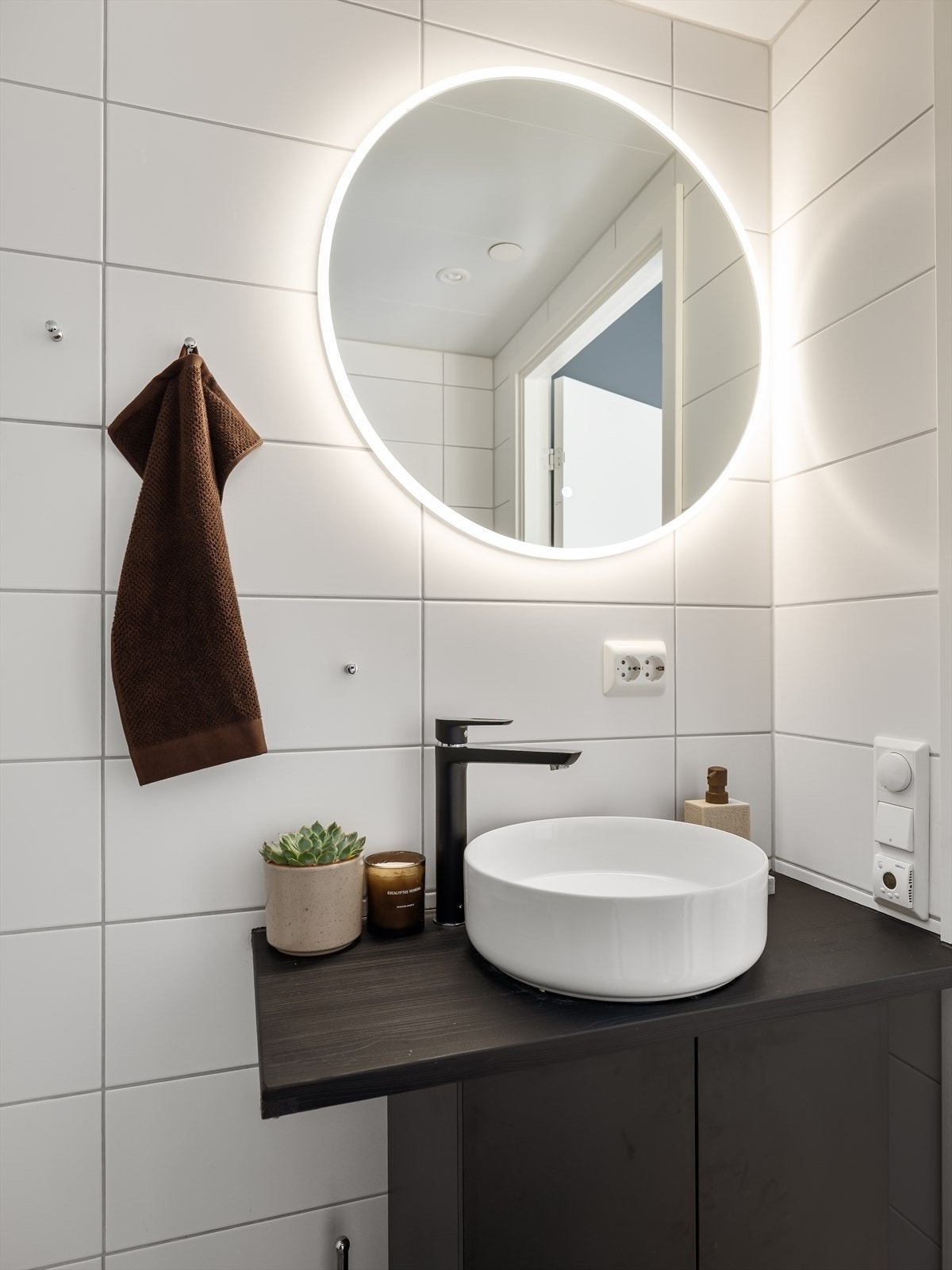 Speil med belysning over servant, dusj med innfellbare dører i herdet glass, servant, veggfestet klosett med innebygget sisterne. Galleribilde