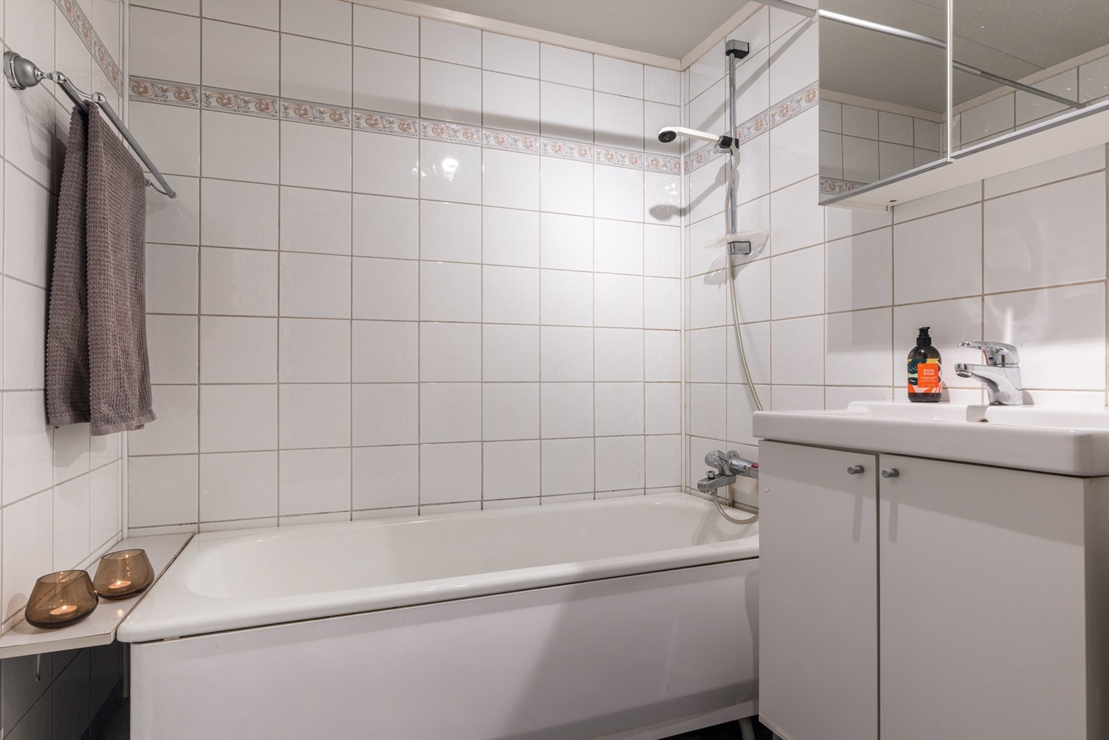 Lyst, flislagt baderom med badekar og servant. Galleribilde