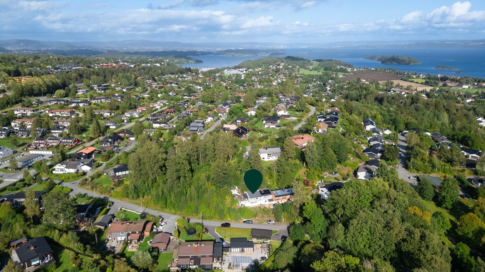 Storslått utsikt over fjorden fra et etablert og frodig boligområde. Galleribilde
