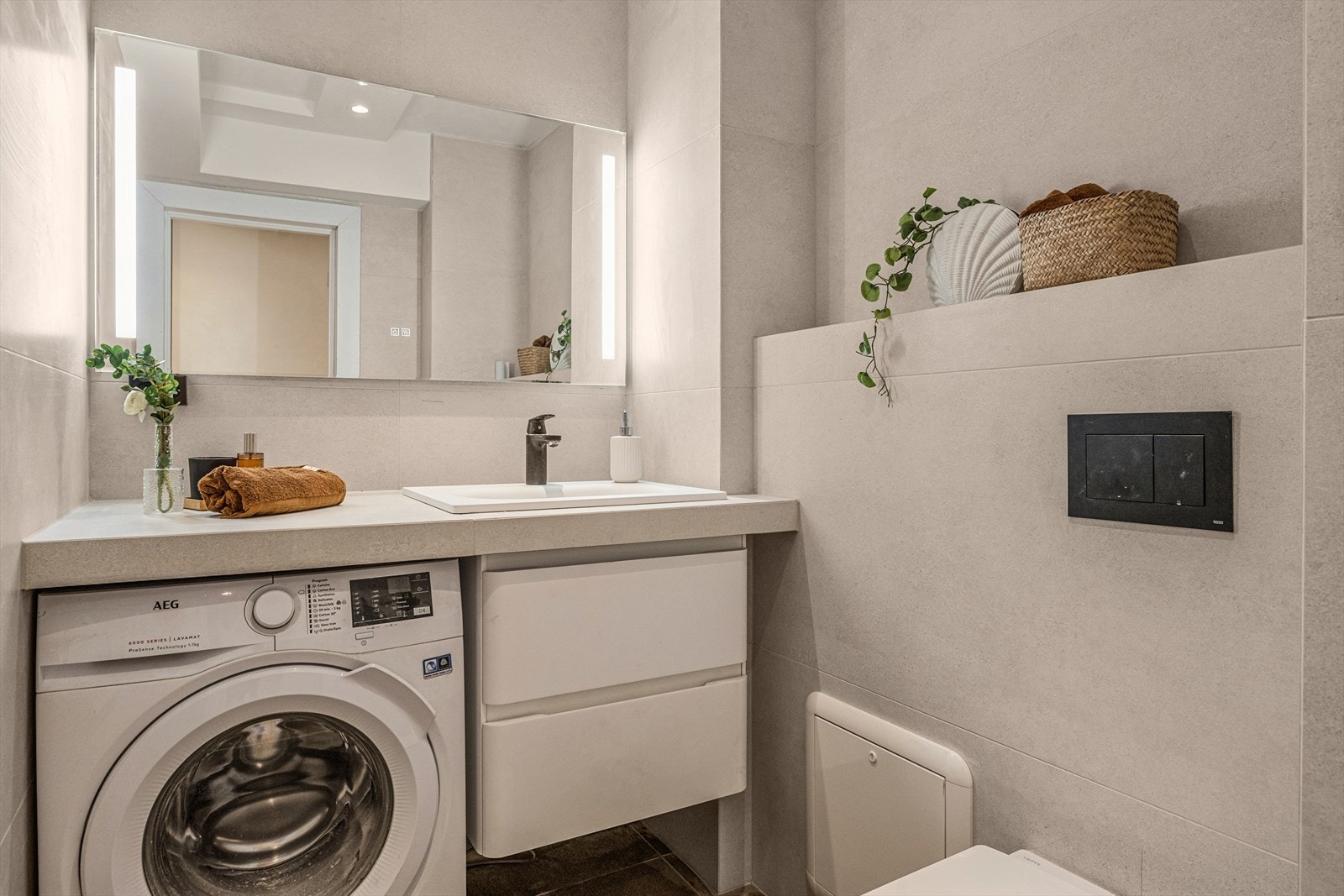 Innredningen består av en servantseksjon med nedfelt vask, vegghengt toalett og et dusjhjørne med glassvegger. Det er også klargjort med opplegg for vaskemaskin. Rommet har balansert ventilasjon. Galleribilde