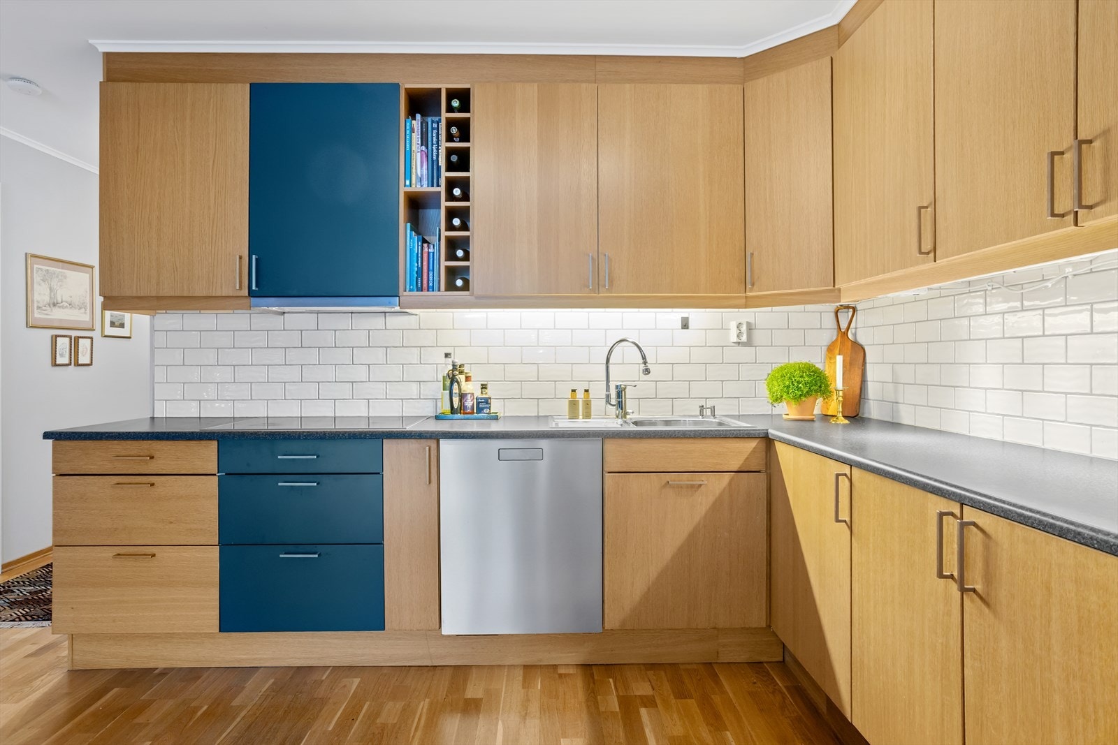 Overskapene er ekstra høyde for god oppbevaringsplass, disse strekker seg nesten helt opp til taket. Foringslist mellom overskapene og himlingen gir et mer elegant uttrykk til innredningen. Alt av hvitevarer er integrert og medfølger. Galleribilde