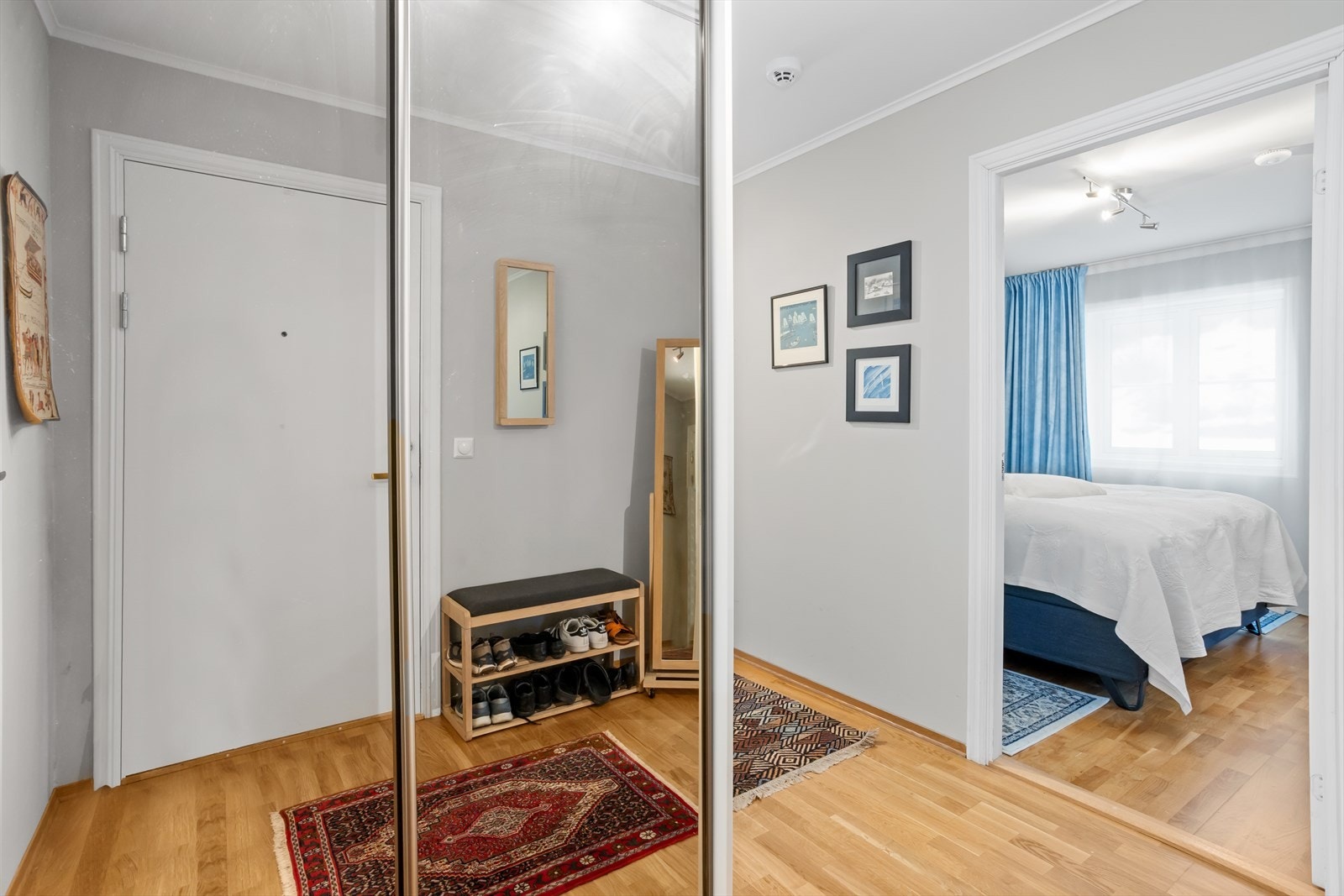 Vel innenfor leilighetens inngangsdør møter man en vid, romslig og lys entre og gang med god plass. I entreèn sørger takhøy speildørsskyvedørsgarderobe for at ytterklær og fottøy kan ryddes pent vekk! Galleribilde